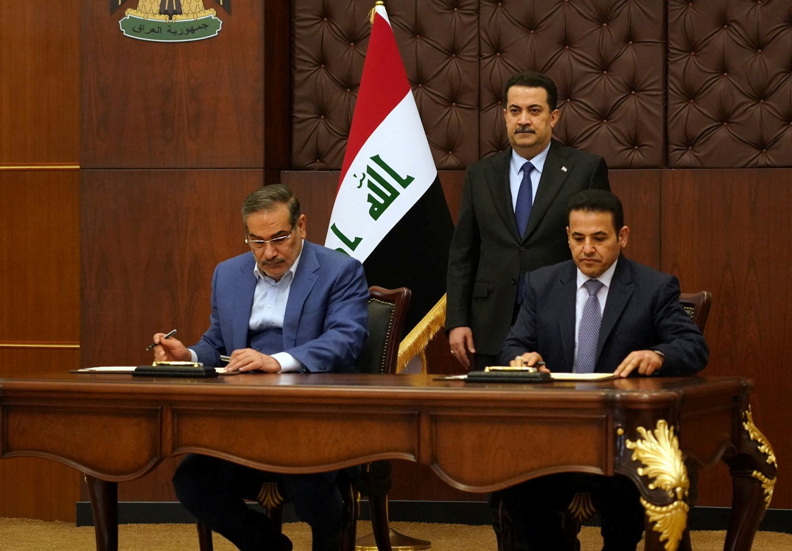 Iraqi Prime Minister Mohammed Shia al-Sudani looks on as Iraq's National Security Adviser Qasim al-Araji and Iran's Supreme National Security Council secretary Ali Shamkhani sign the security agreement that includes coordination in protecting the common borders between the two countries, in Baghdad, Iraq, March 19, 2023. Iraqi Prime Minister Media Office/Handout via REUTERS ATTENTION EDITORS - THIS IMAGE WAS PROVIDED BY A THIRD PARTY.