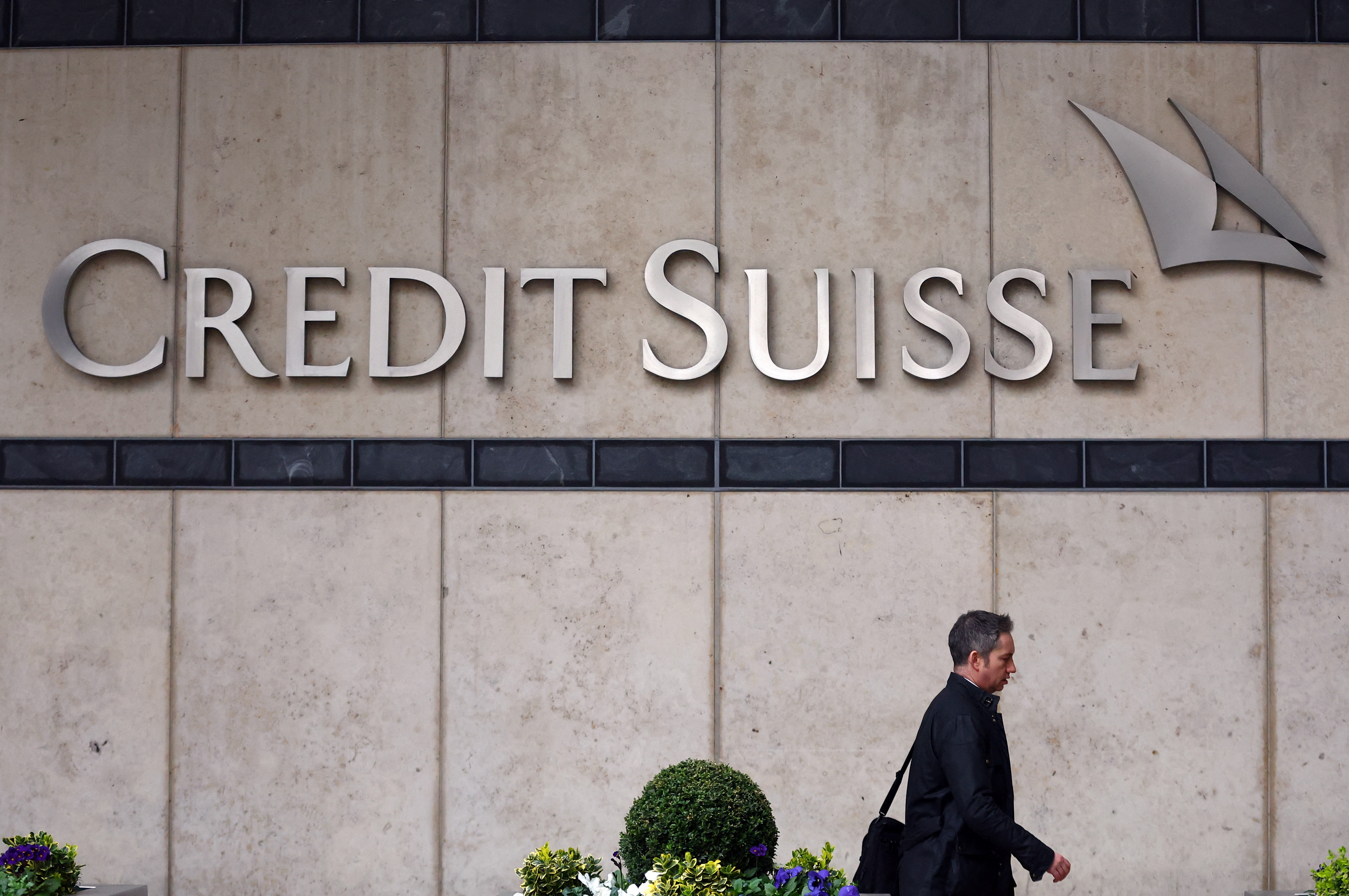 A person walks past the Credit Suisse office in Canary Wharf in London