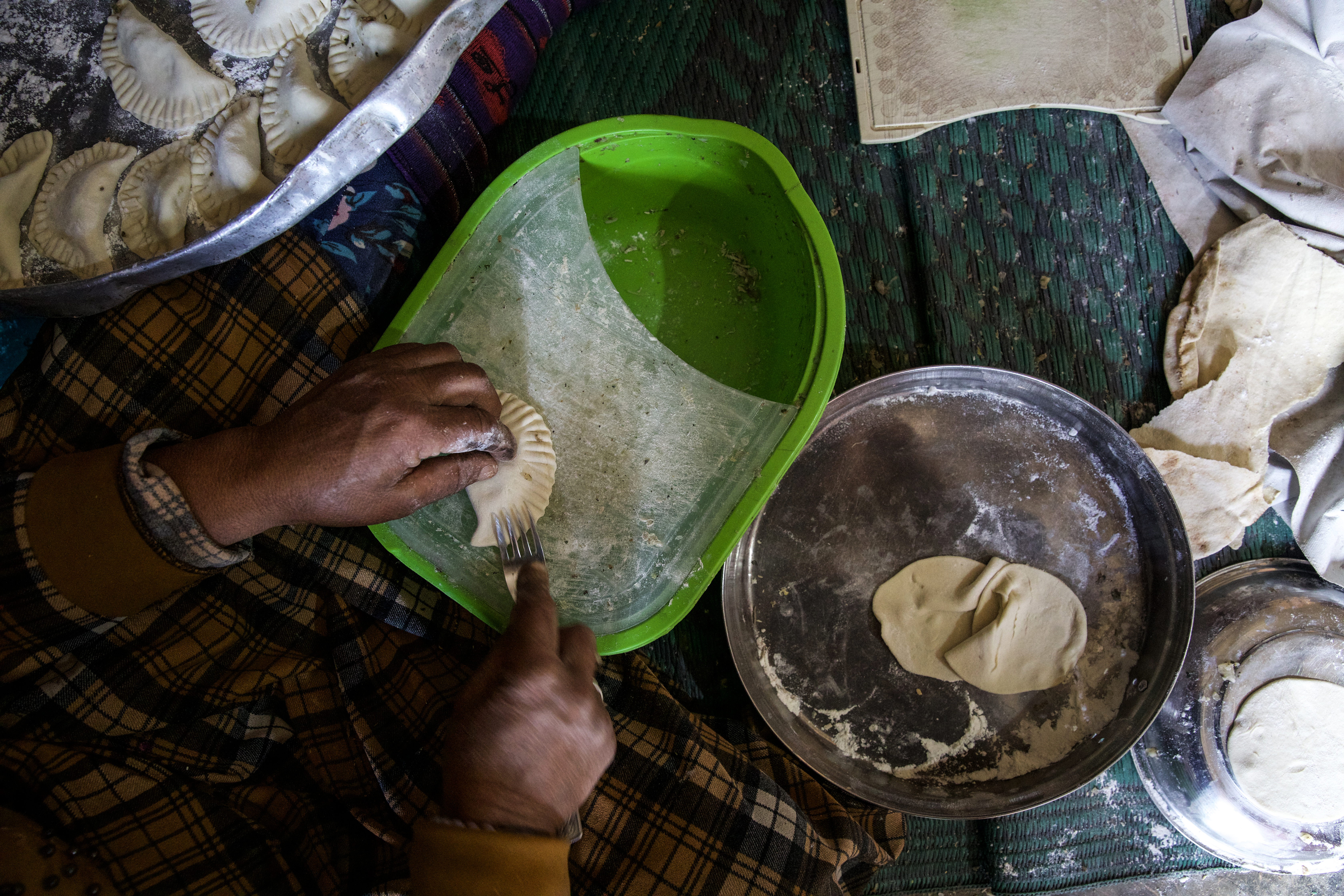 Fateem's hands crimp the edges of a sambousik with a fork