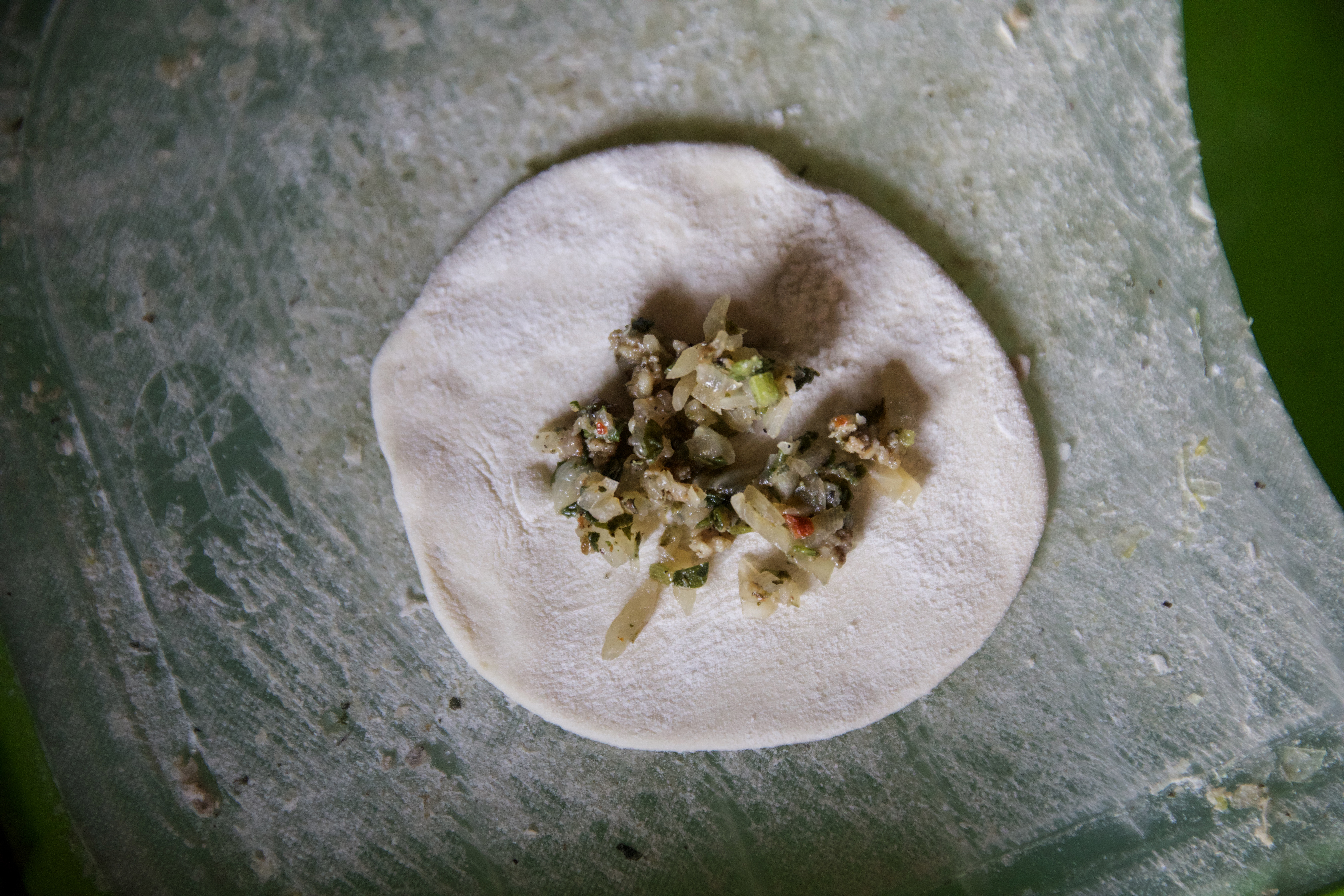 View of a circle of dough with its filling on it before it is sealed