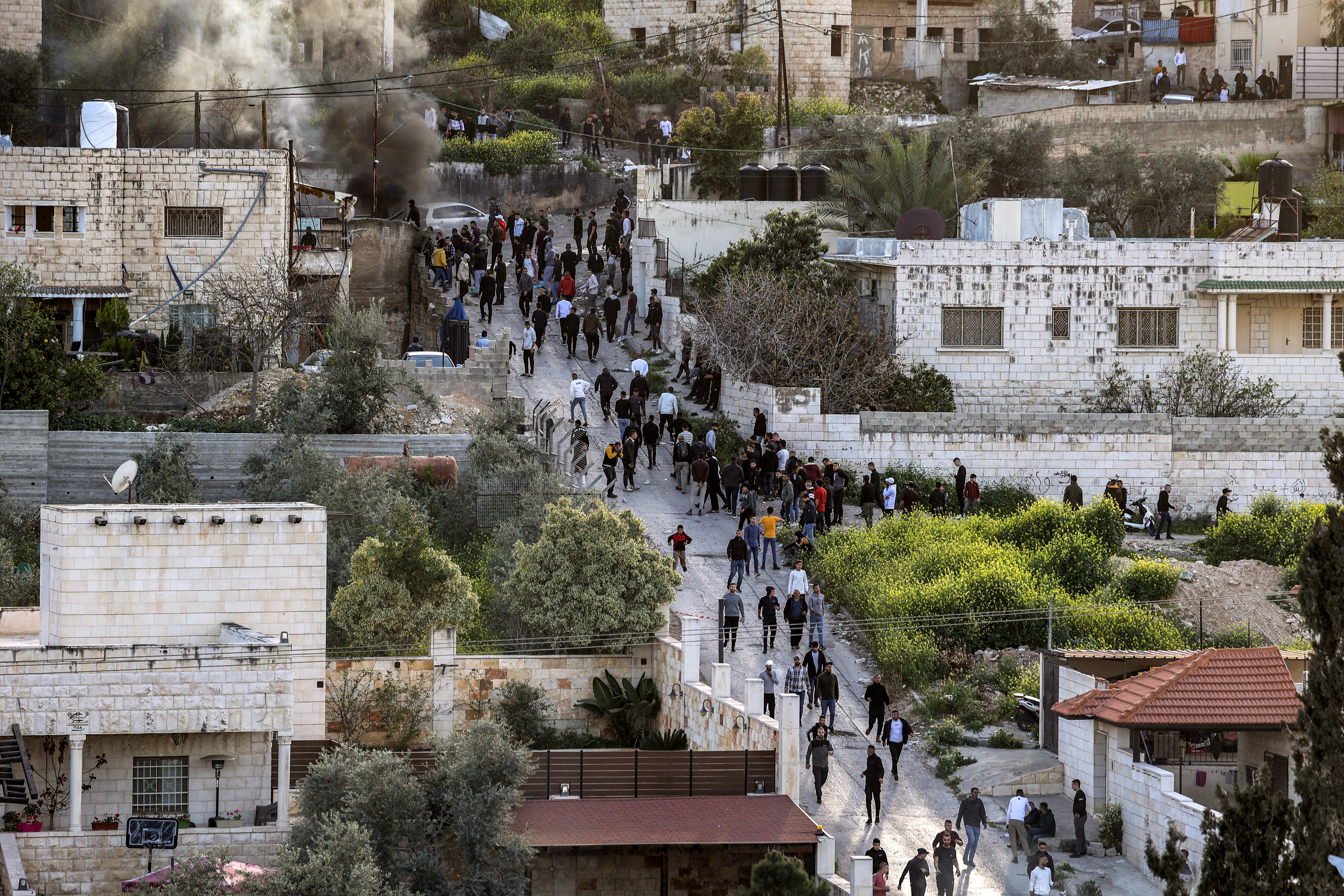People gather along a road during an Israeli army raid in the Jenin camp for Palestinian refugees in the occupied West Bank on March 7, 2023. - Israeli troops killed one Palestinian and wounded several others in a raid in Jenin on March 7, the Palestinian health ministry said. Witnesses in the refugee camp reported heavy gunfire between militants and soldiers as the Israeli forces surrounded a house.