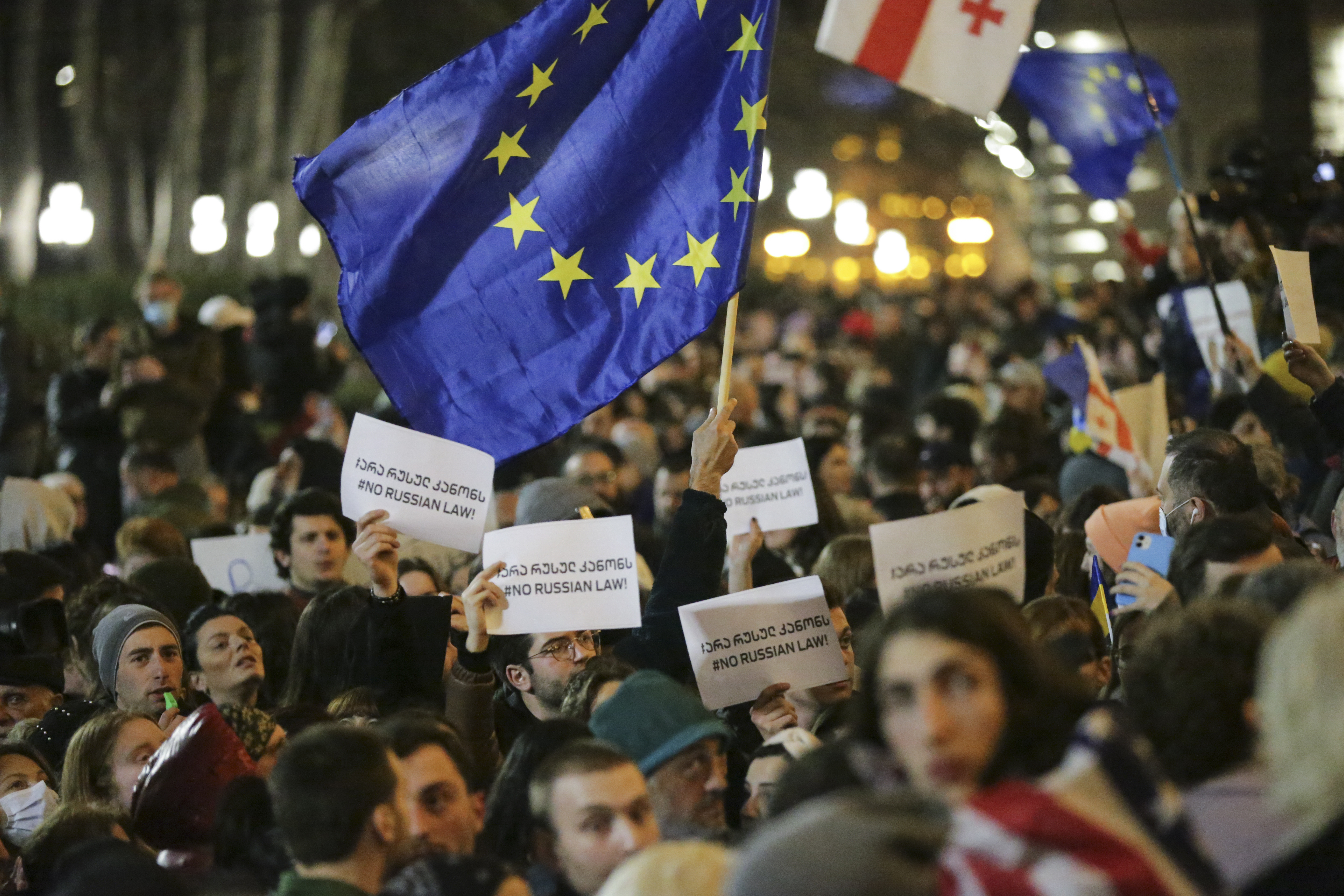 Protesters in Tbilisi brandish placards and a European Union flag 