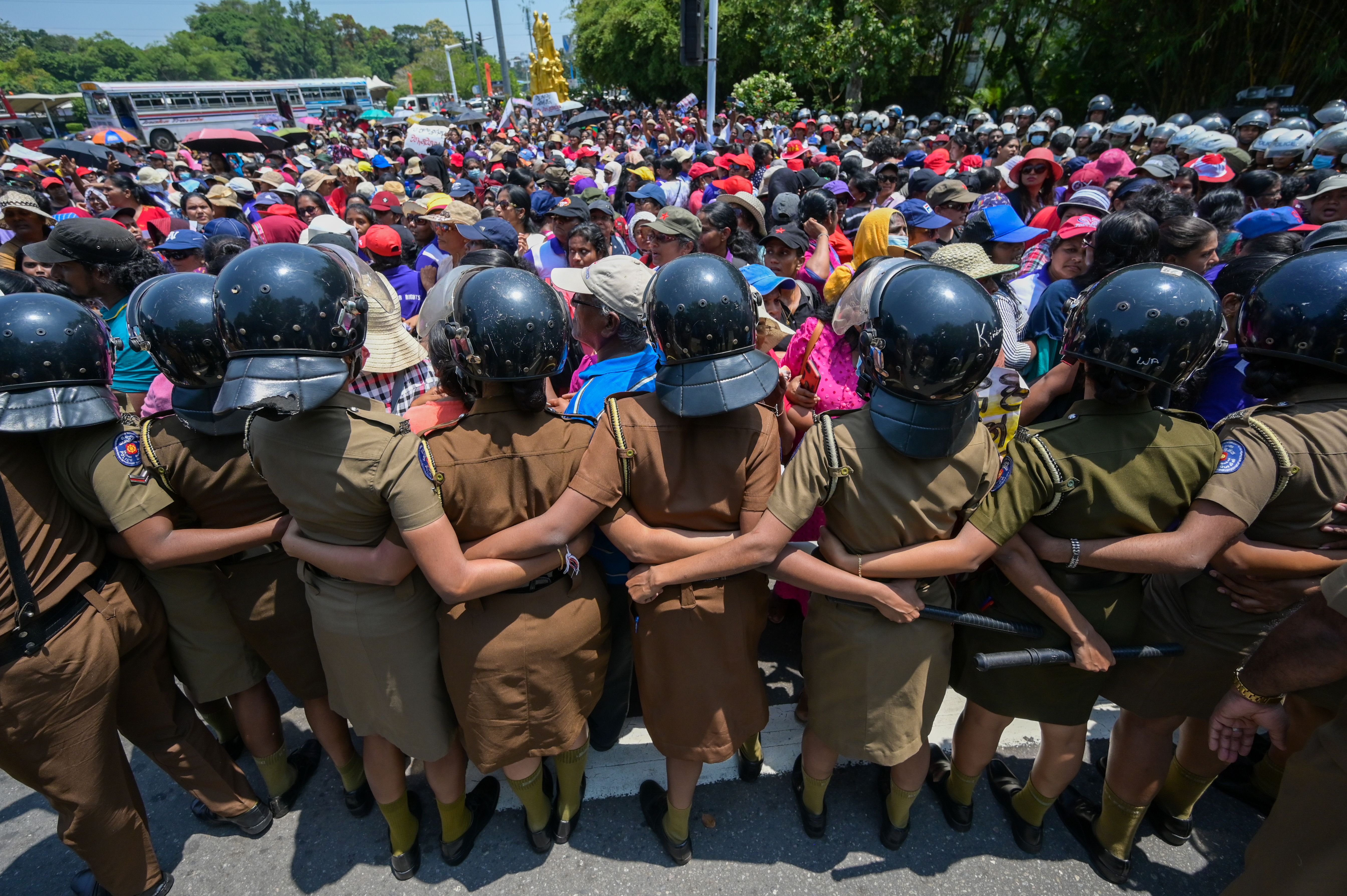 Policewoman stand guard as anti-government demonstrators take part in a protest organised by the "Women for Rights" group on the occasion of International Women's Day against the proposed tax reforms and the country's economic crisis, near the parliament building in Colombo on March 8, 2023. (Photo by ISHARA S. KODIKARA / AFP)