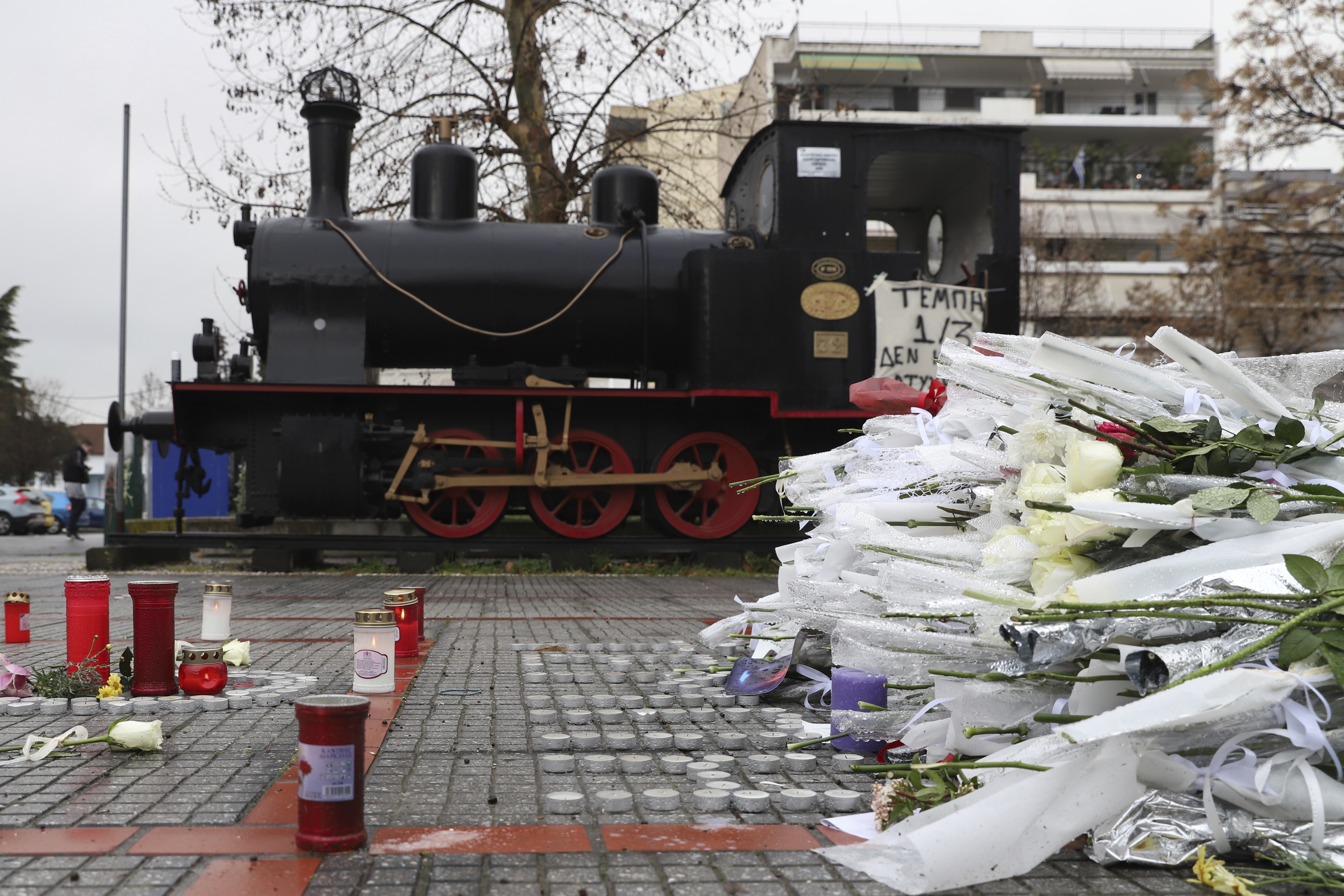 Flowers and candles lie in the memory of the victims of a deadly train crash outside a train station of Larissa city, north of Athens, Greece, Thursday, March 2, 2023. Emergency workers are searching late into the night for survivors and bodies after a passenger train and a freight train crashed head-on in Tempe, central Greece just