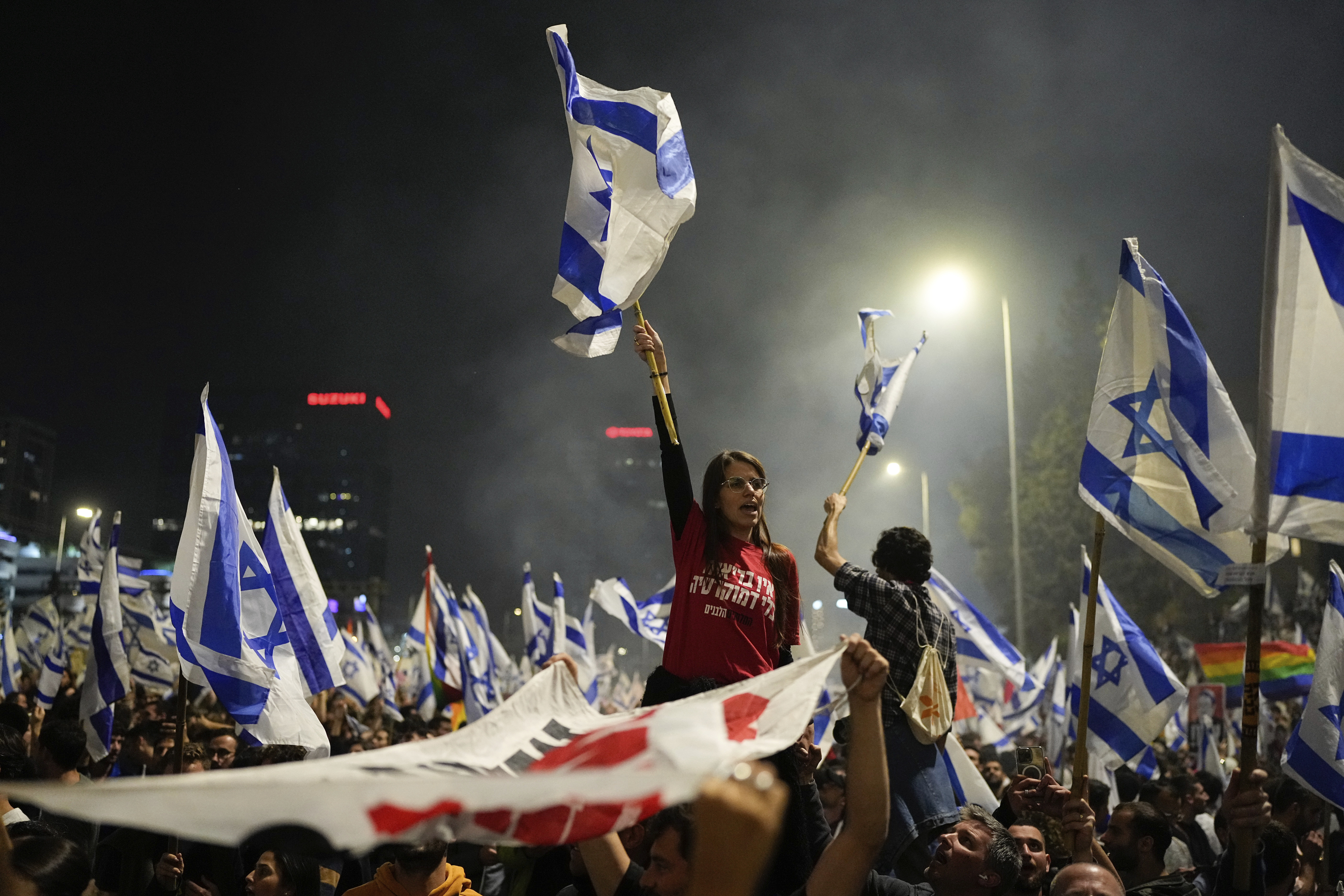 Hundreds of Israeli protesters, many holding flags of Israel over their heads, block a highway in Tel Aviv, Israel.
