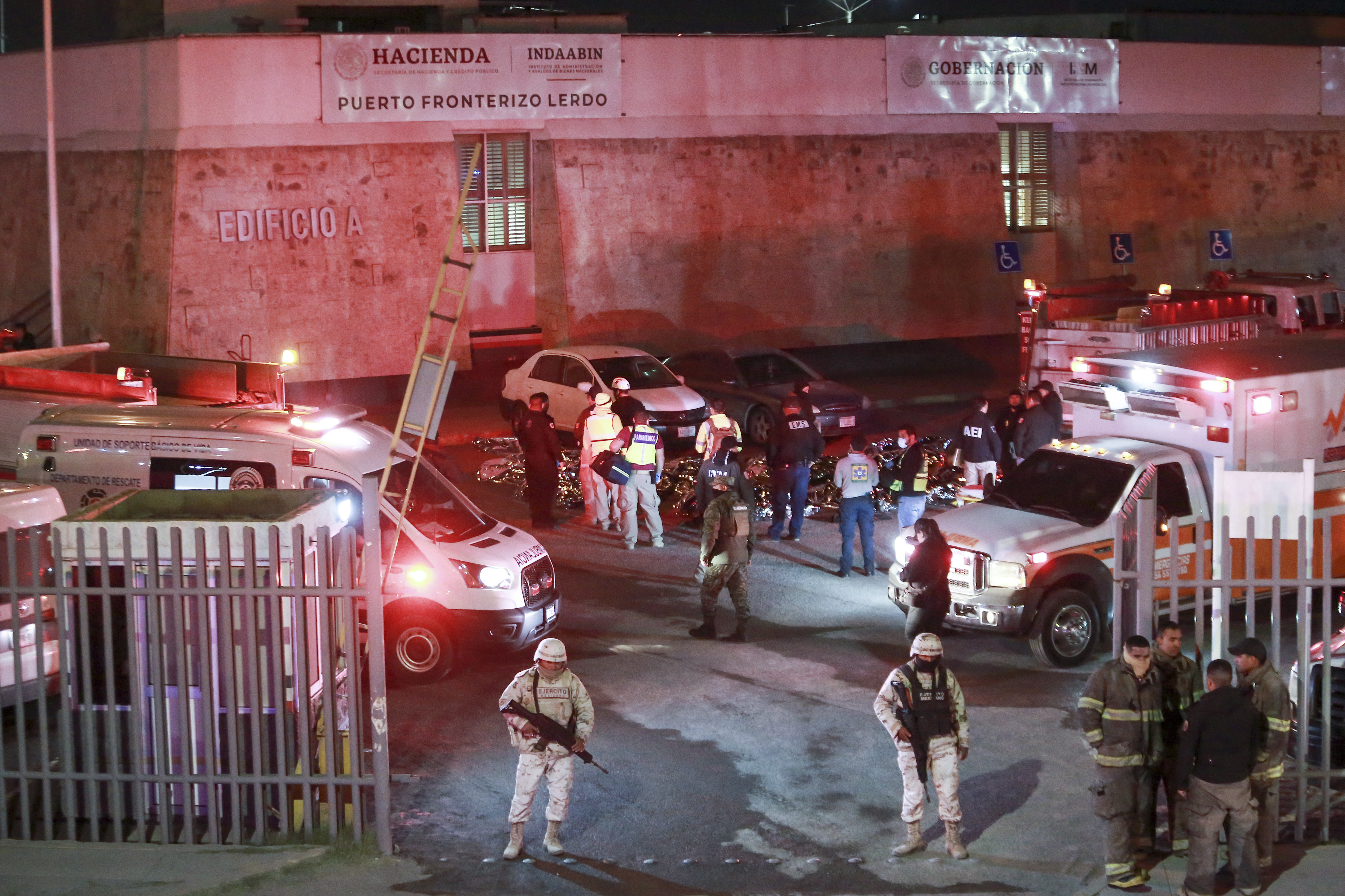 Paramedics and security forces work amid the covered bodies of migrants who died in a fire at an immigration detention center in Ciudad Juarez, Mexico