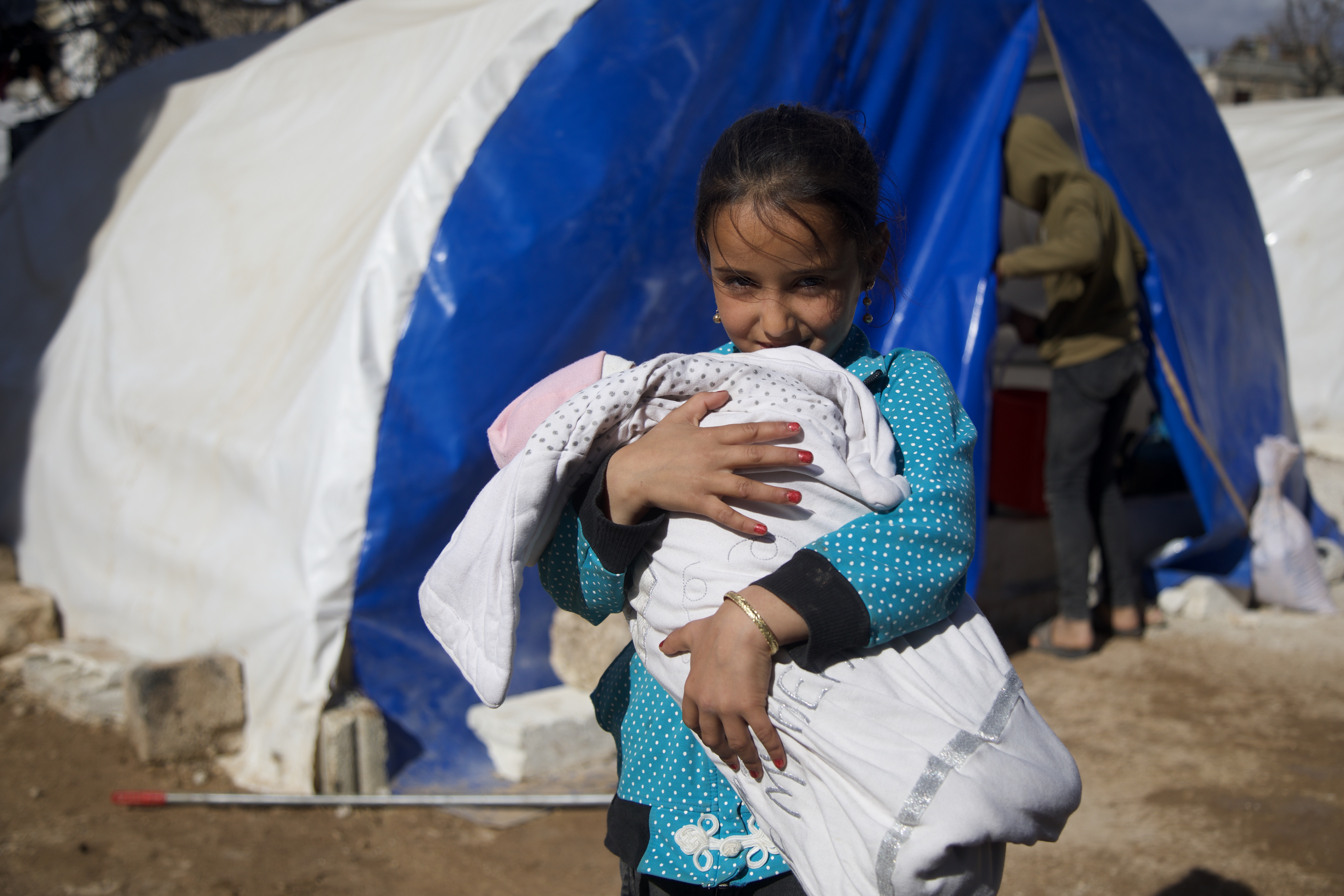 Doaa holds Afraa in her arms outside the family tent