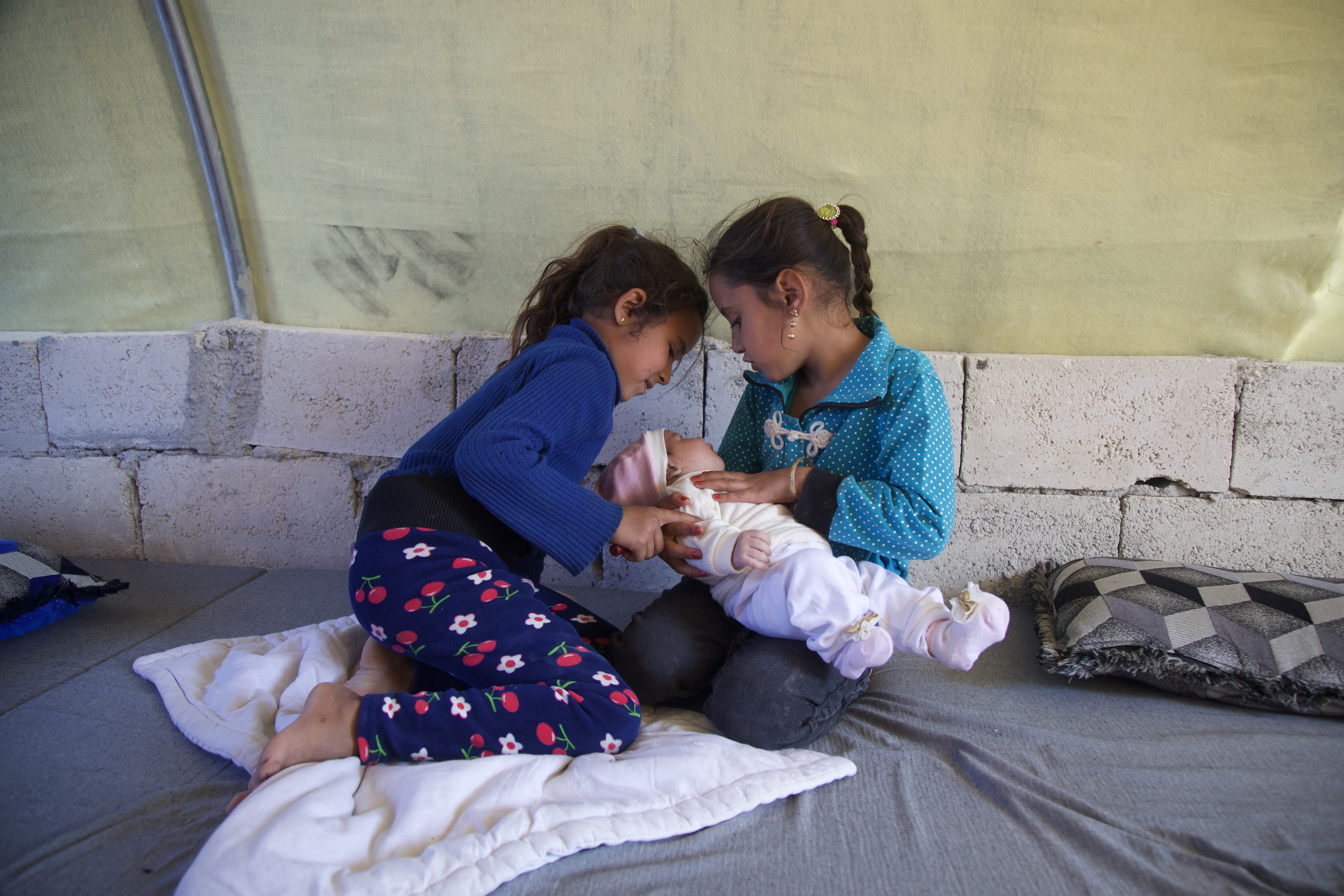 Mariam and Doaa coo over and cuddle baby Afraa in their tent
