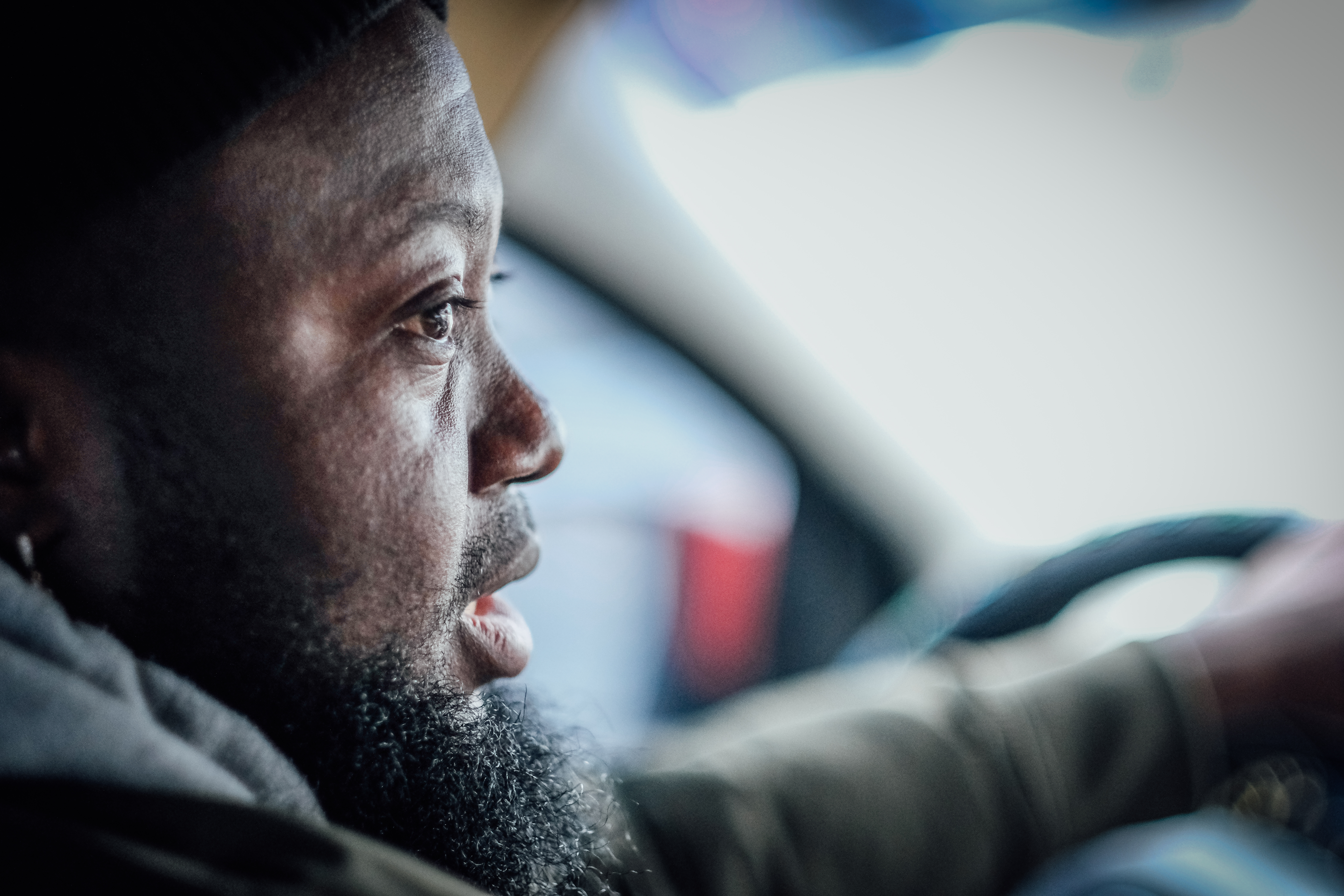A photo of Nelly Nelson from the side, driving a car.