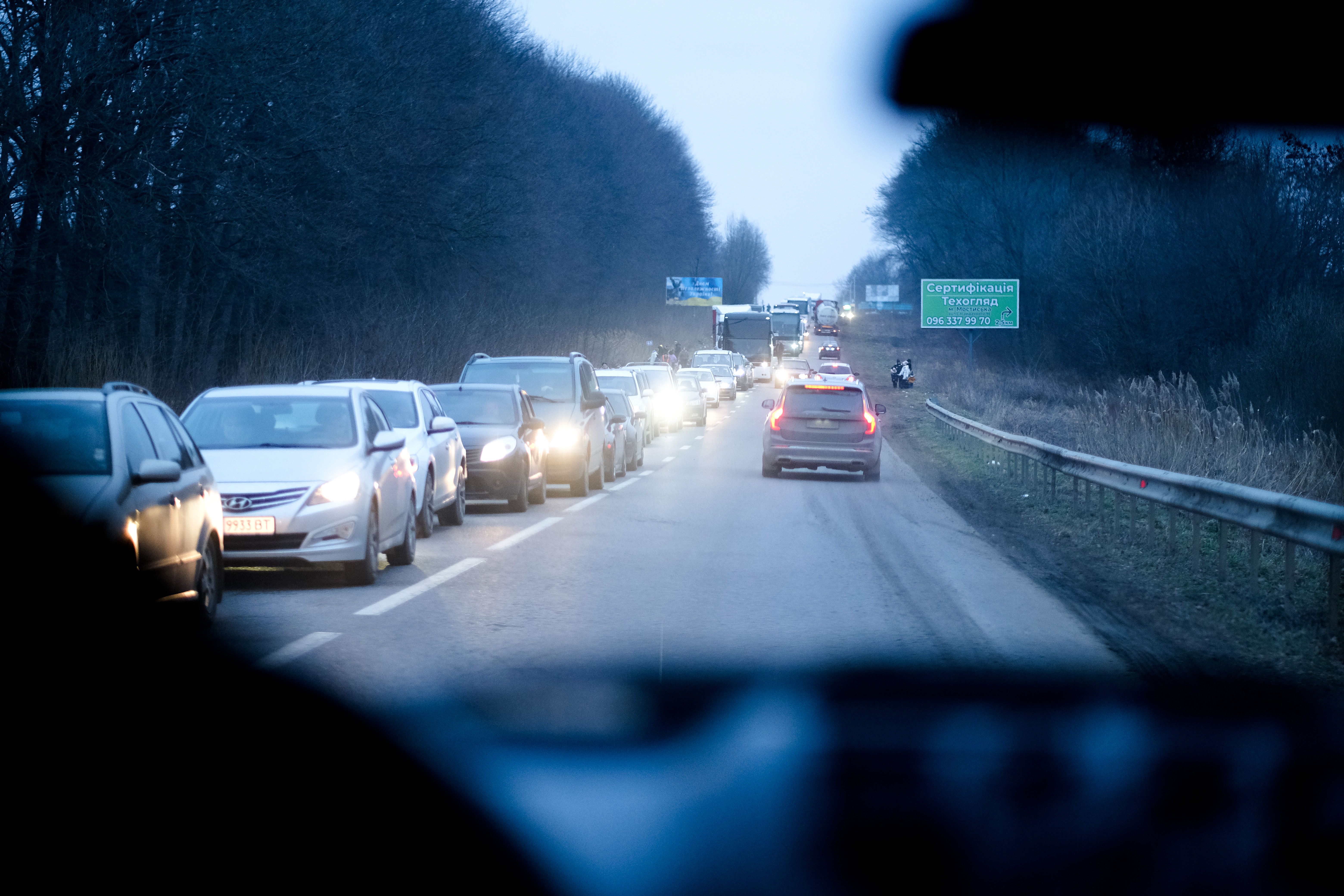 A photo of a very long line of cars on the left side of the road with cars moving on the right.