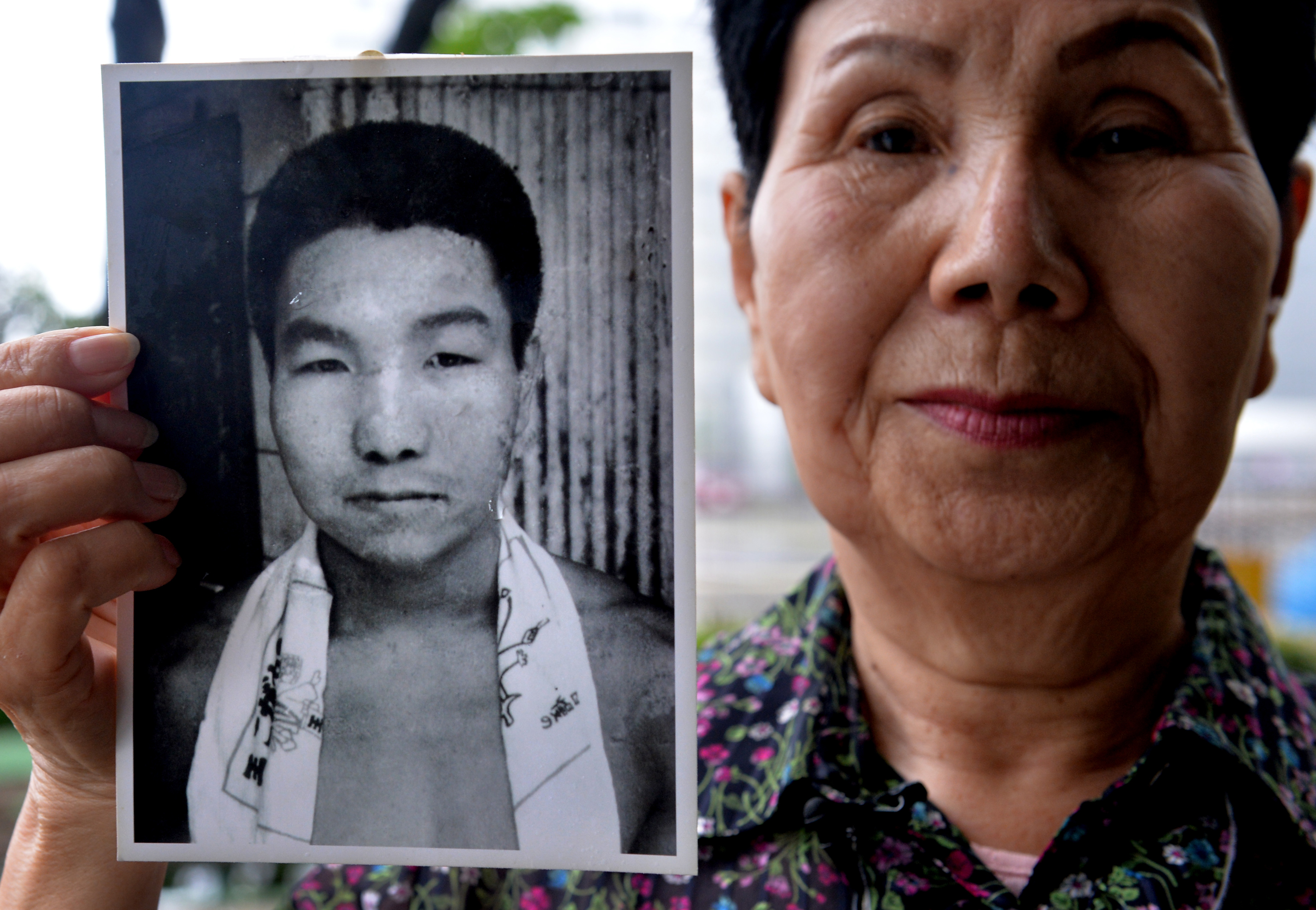 Hideko holding up a picture of her brother as a young man.