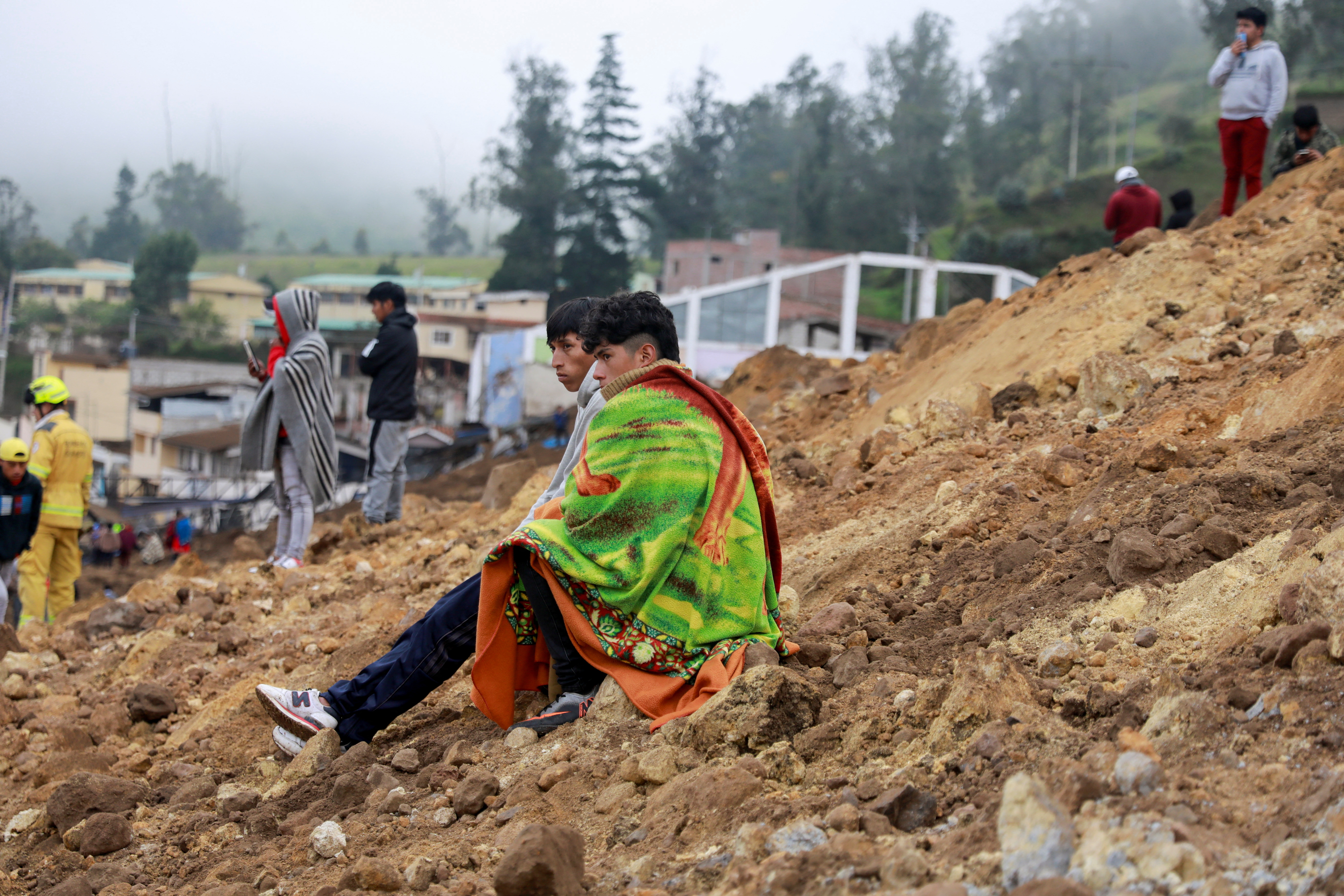People sit on debris after a landslide