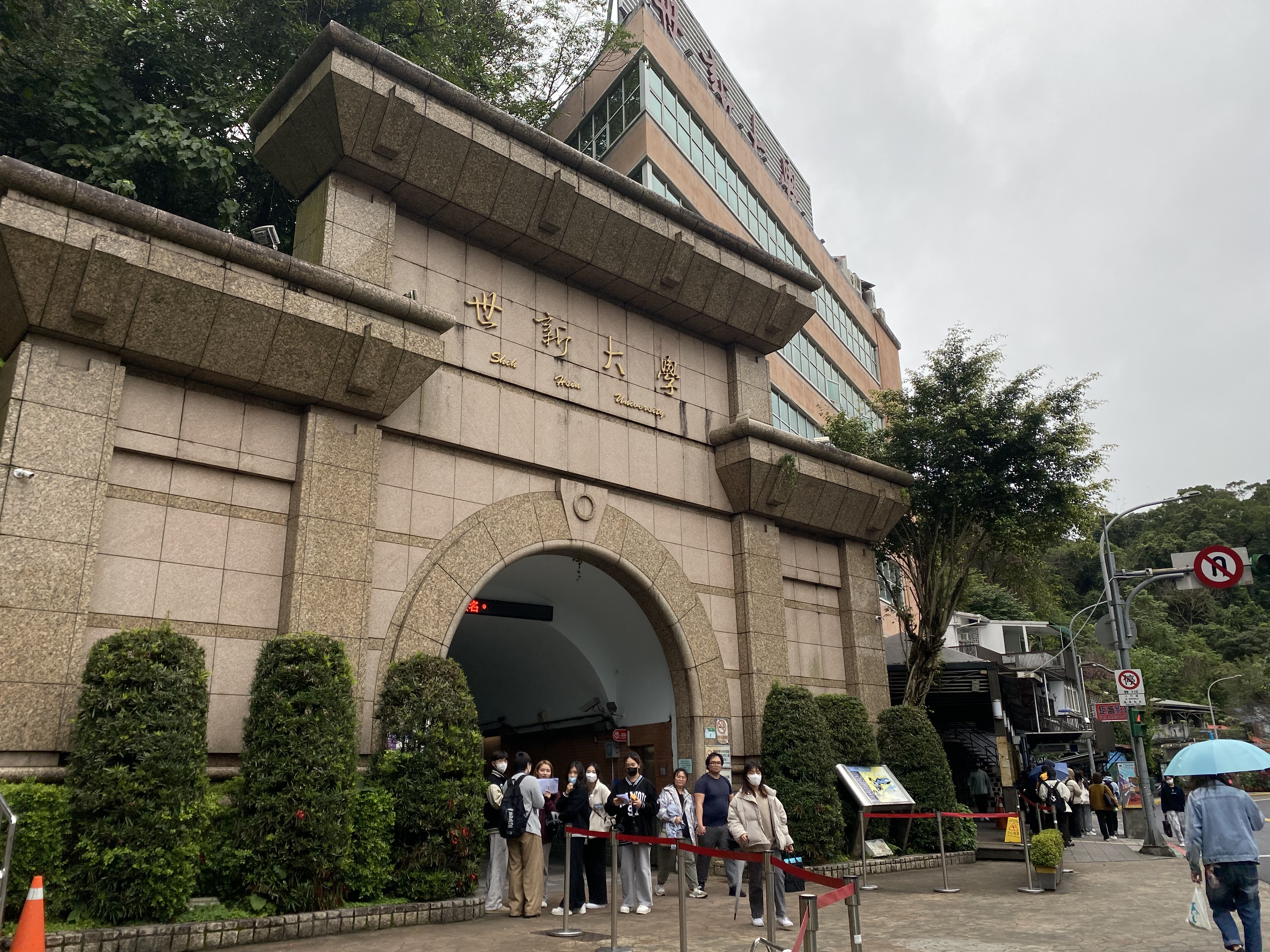 A view of Shih Hsin University in Taipei with students walking out from an archway