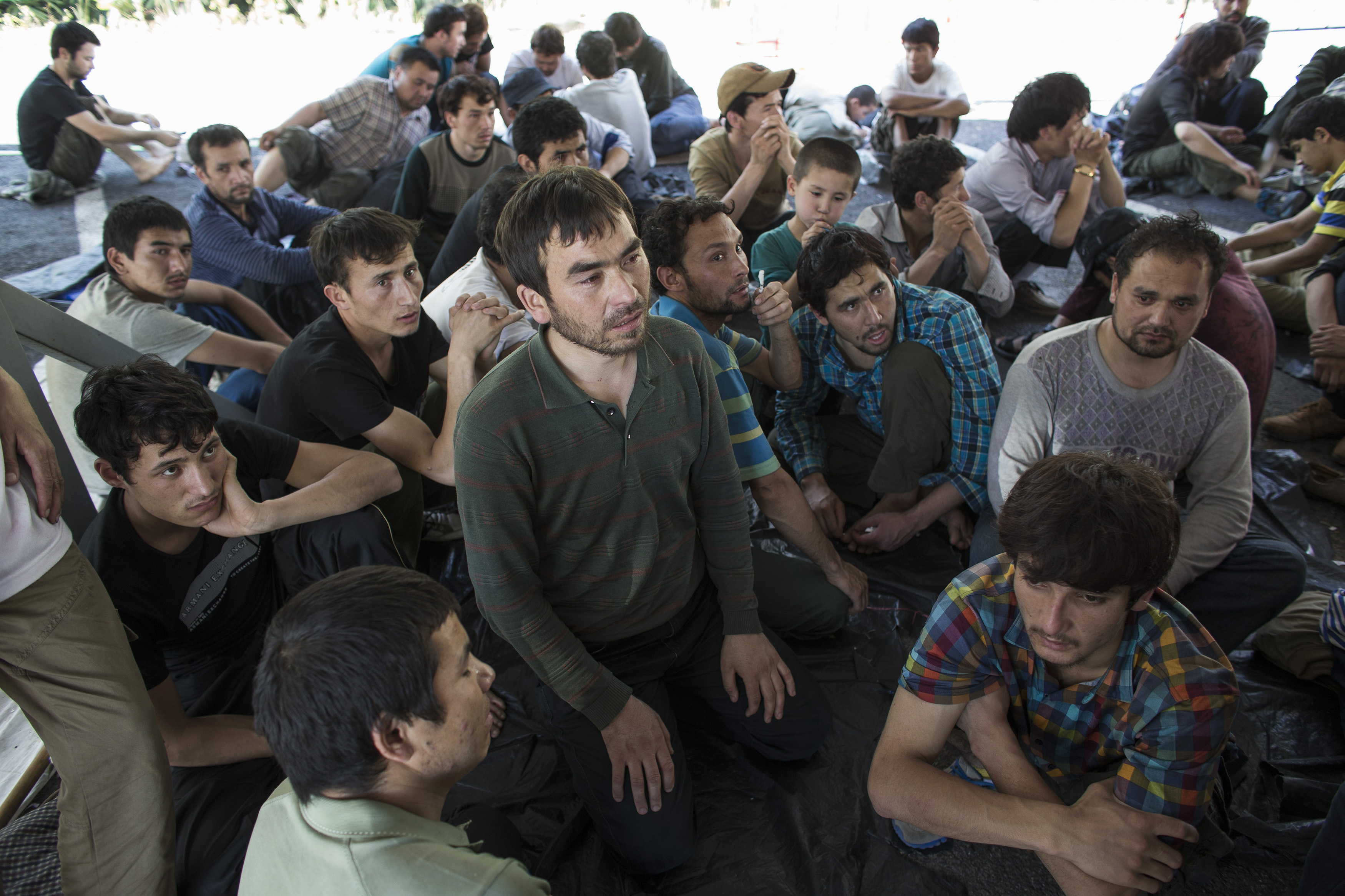 A group of Uighur refugees looking scared after being detained in Thailand near the border with Malaysia. The group includes men, women and children.