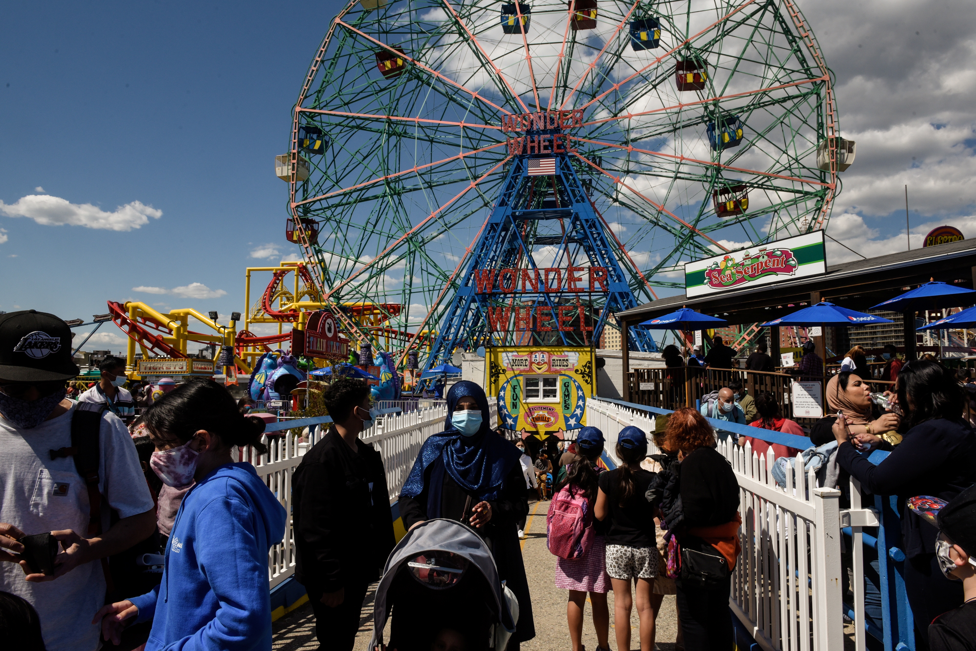 People walk in front of a ferris wheel