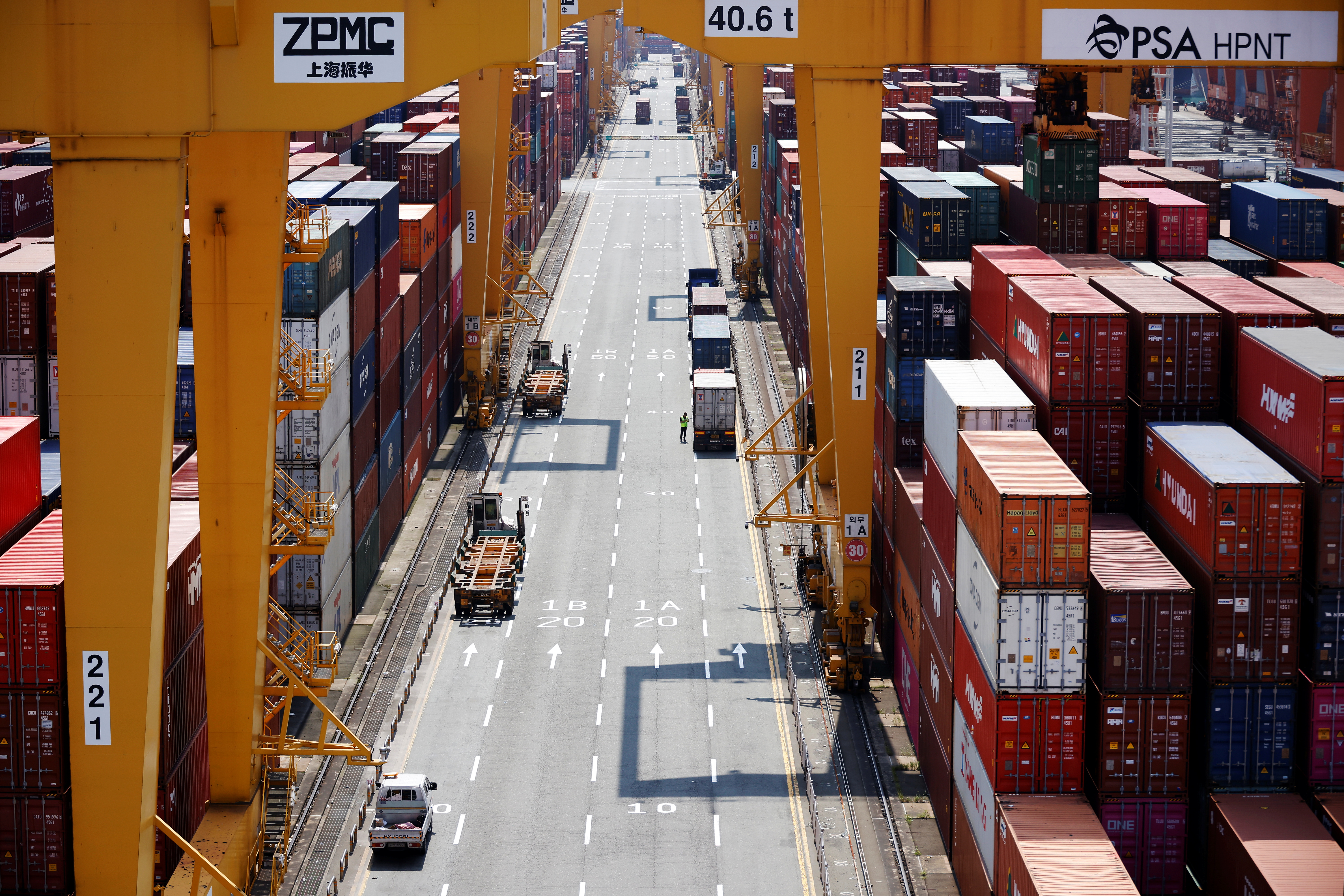 A truck driver stands next to his truck as he gets ready to transport a shipping container at Pusan Newport Terminal in Busan, South Korea.