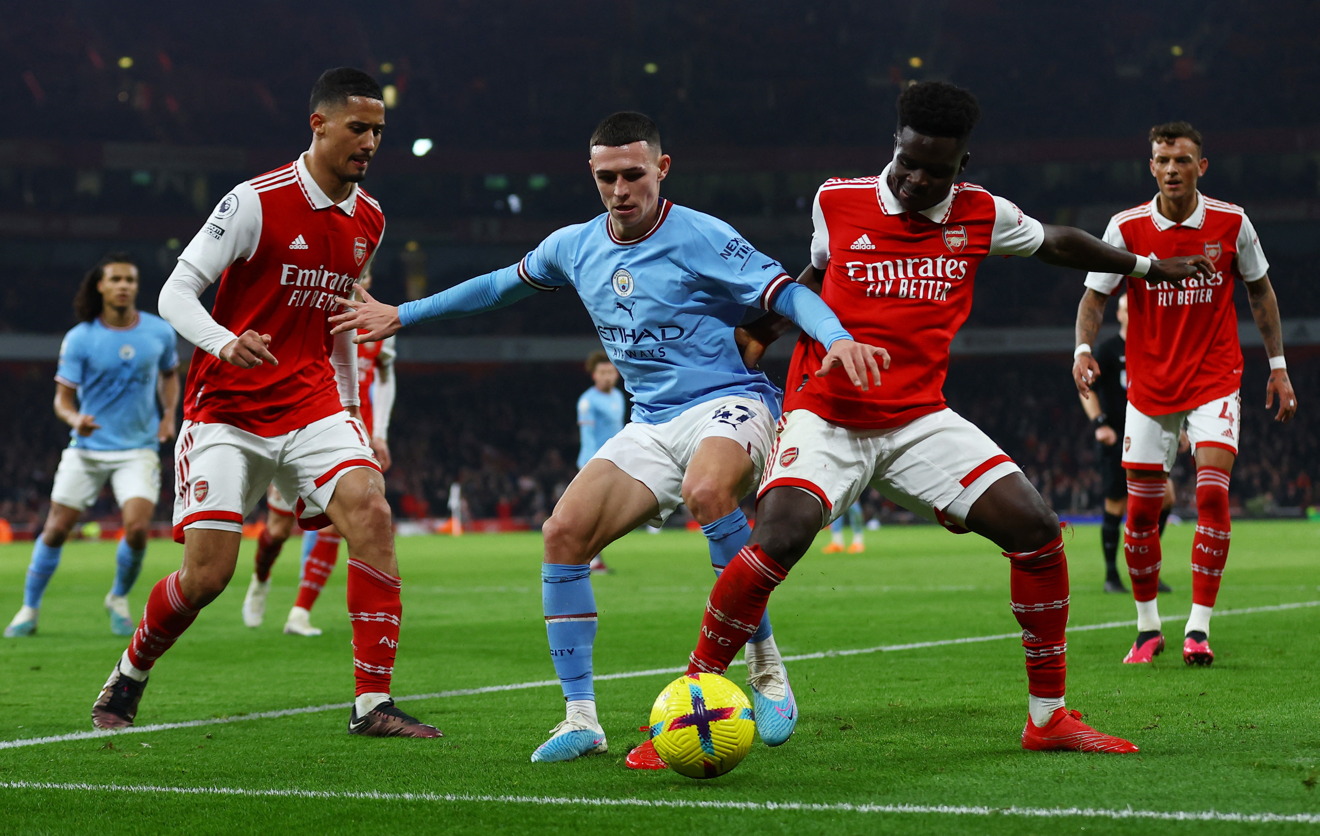 Arsenal's William Saliba and Bukayo Saka in action with Manchester City's Phil Foden