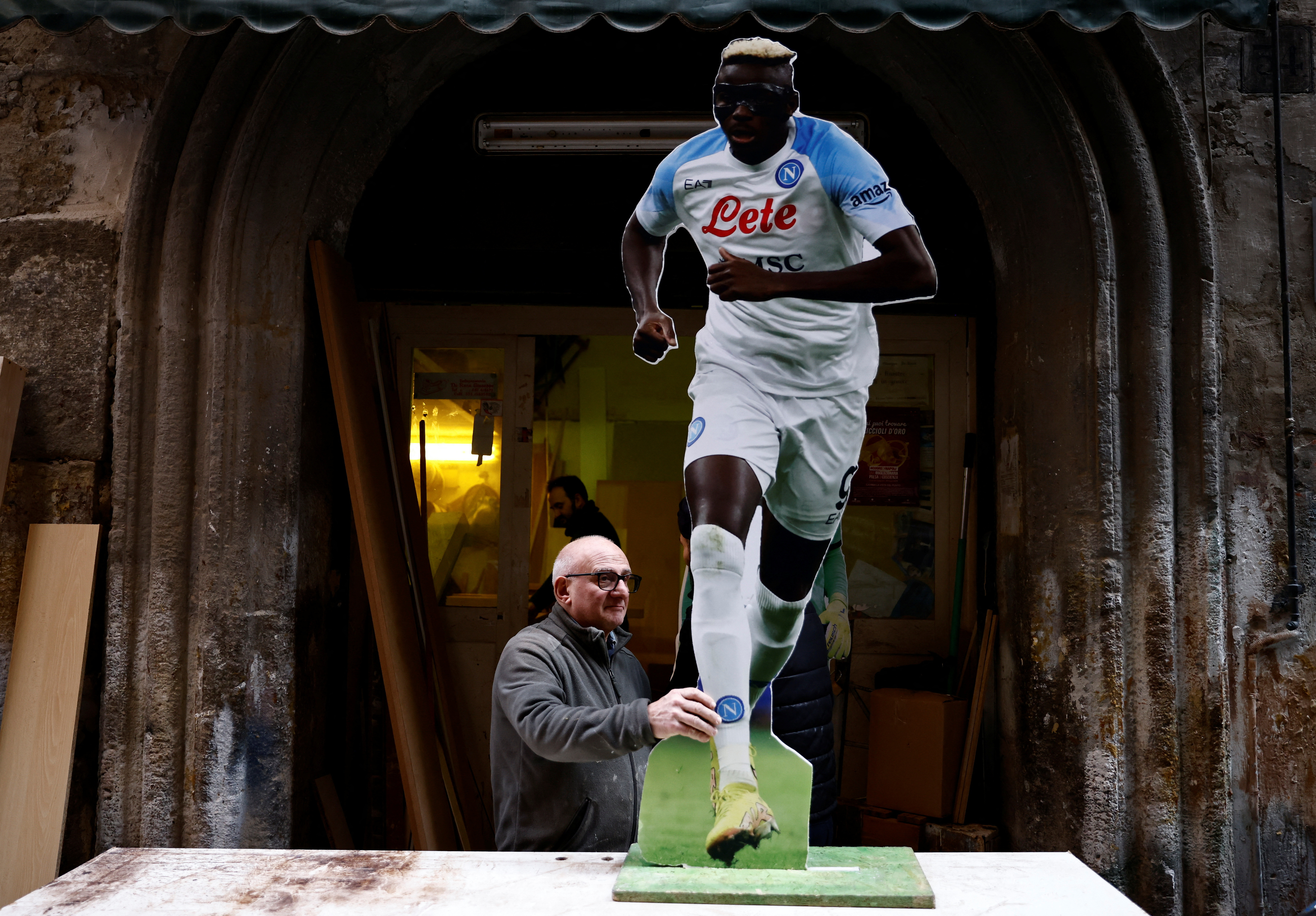 Giuseppe de Rosa fixes a cardboard cutouts of Napoli's Victor Osimhen in the Spanish quarters of Naples