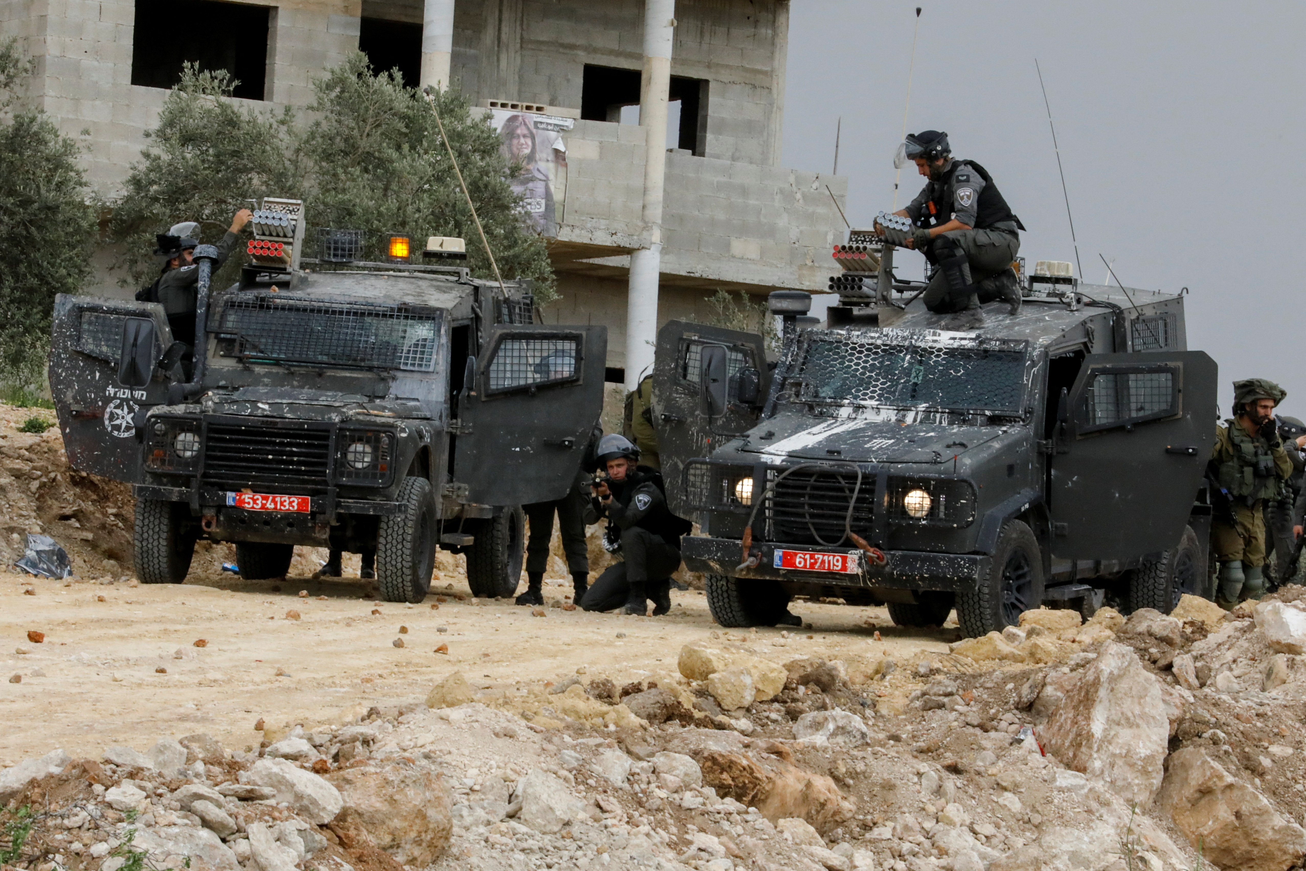 An Israeli border police officer aims his weapon as another prepares to fire tear gas canisters towards Palestinian demonstrators protesting against Israeli settlements near Nablus in the Israeli-occupied West Bank, April 10, 2023