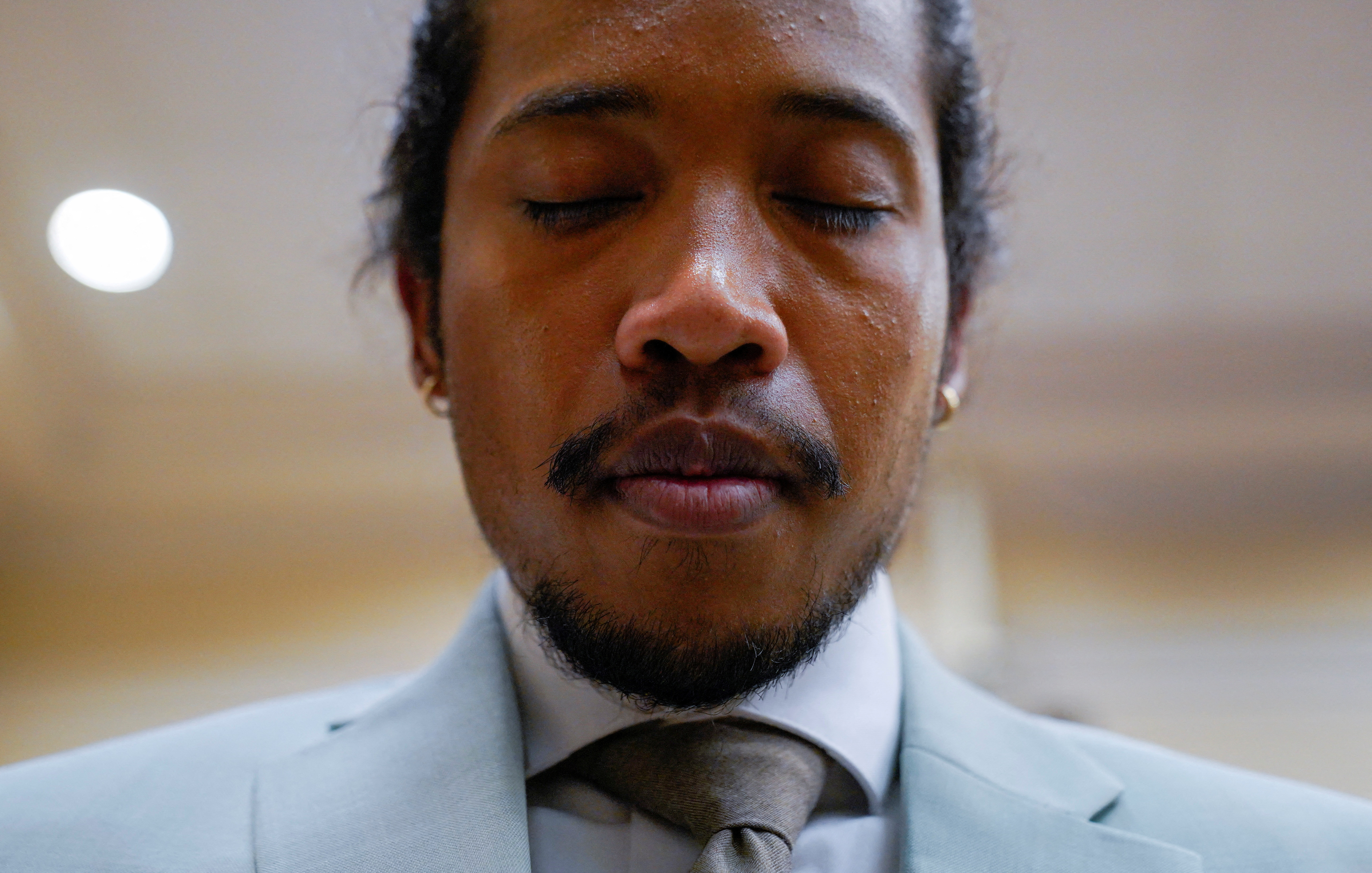 A close-up of Justin Jones with eyes closed in prayer