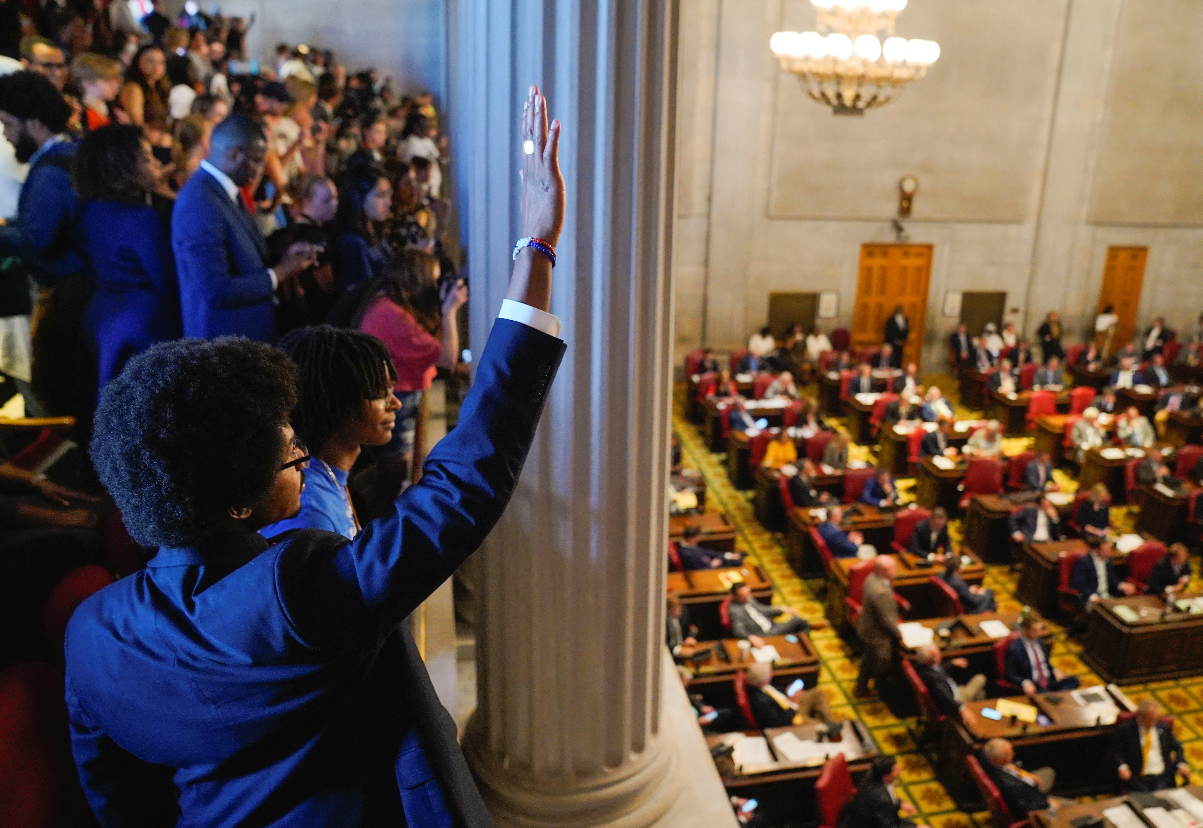 Justin Pearson lifts an arm and waves from a gallery above the legislature