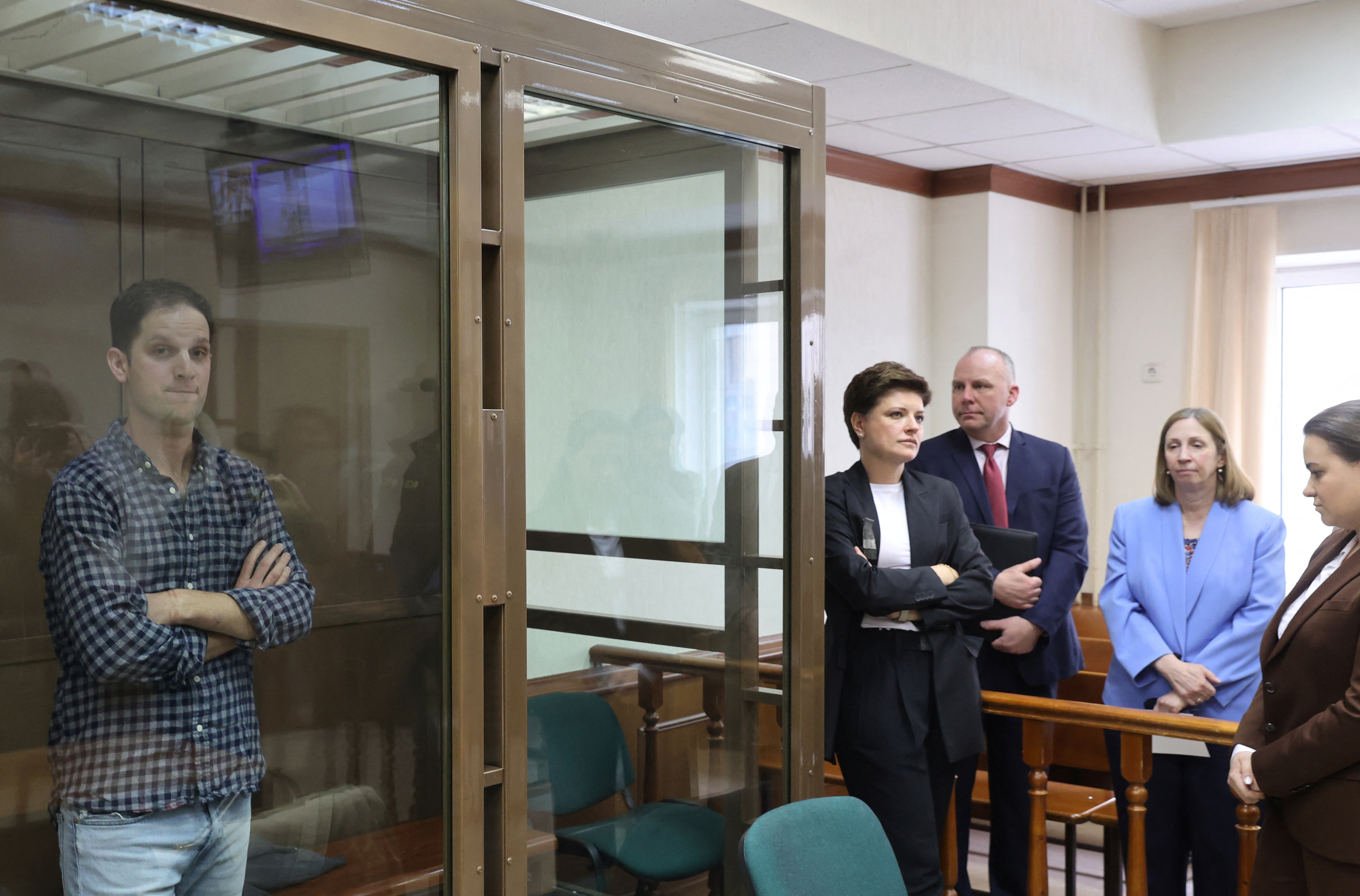 Wall Street Journal reporter Evan Gershkovich, who was detained in March while on a reporting trip and charged with espionage, stands behind a glass wall of an enclosure for defendants, while U.S. Ambassador to Russia Lynne Tracy and lawyers Tatyana Nozhkina and Maria Korchagina appear in a courtroom before a hearing to consider an appeal against Gershkovich's detention, in Moscow, Russia April 18, 2023