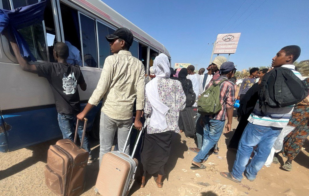 People crowding around a bus in Khartoum as they flee the city.