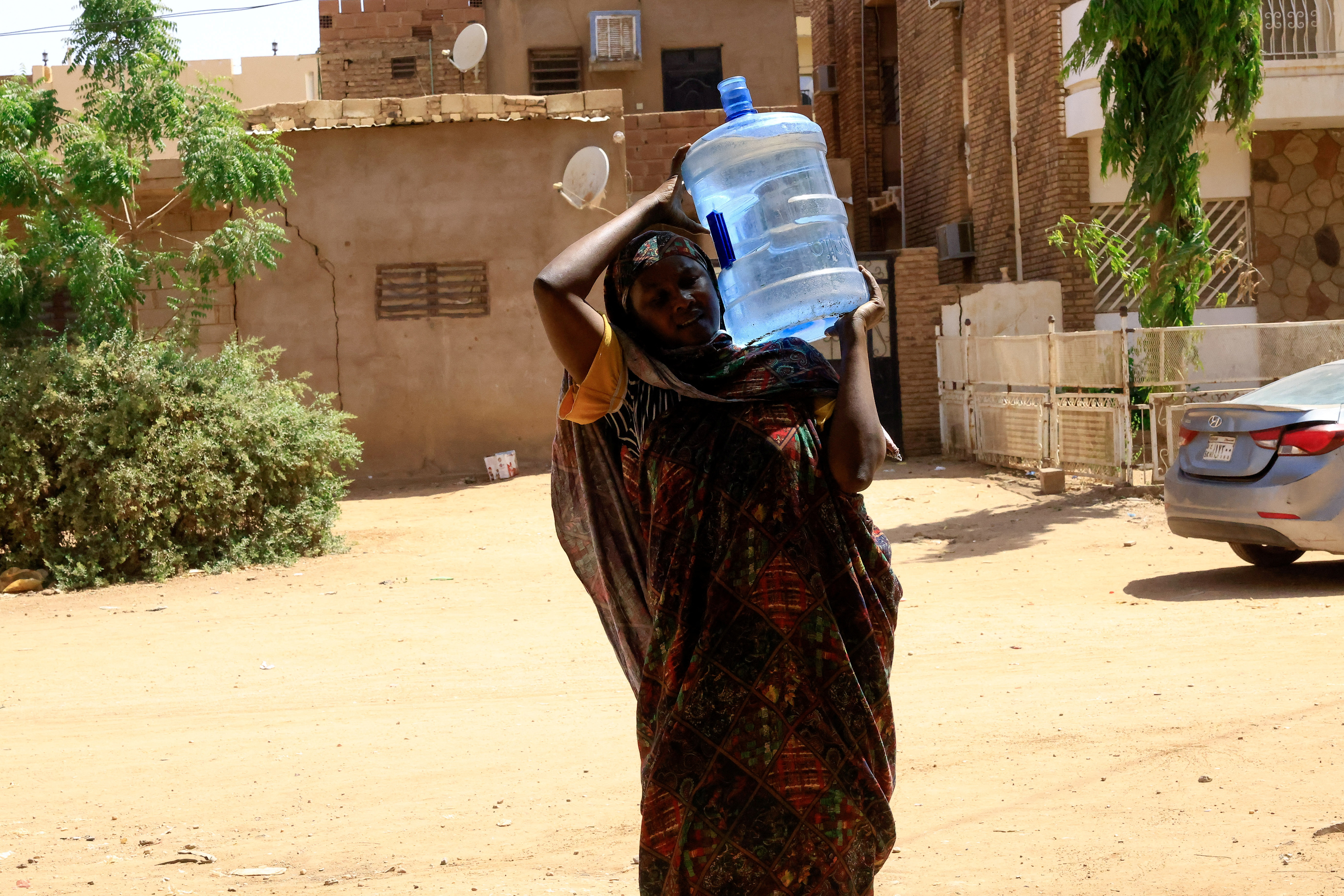 A woman carries a gallon of water in Sudan during fighting