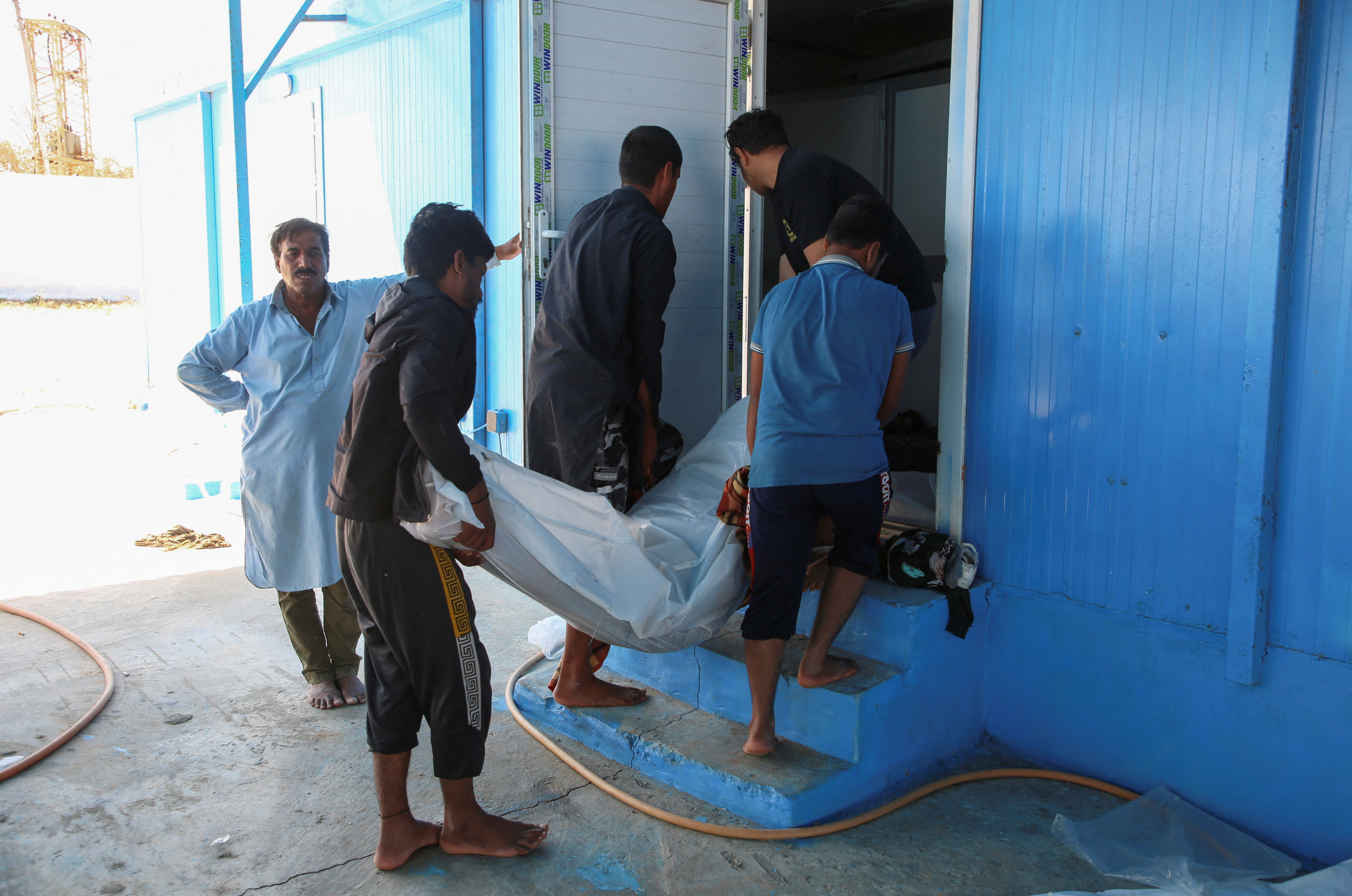 People carry the body of a migrant, whose boat sank in the sea, after the Libyan Coast Guards took them out from the Mediterranean Sea