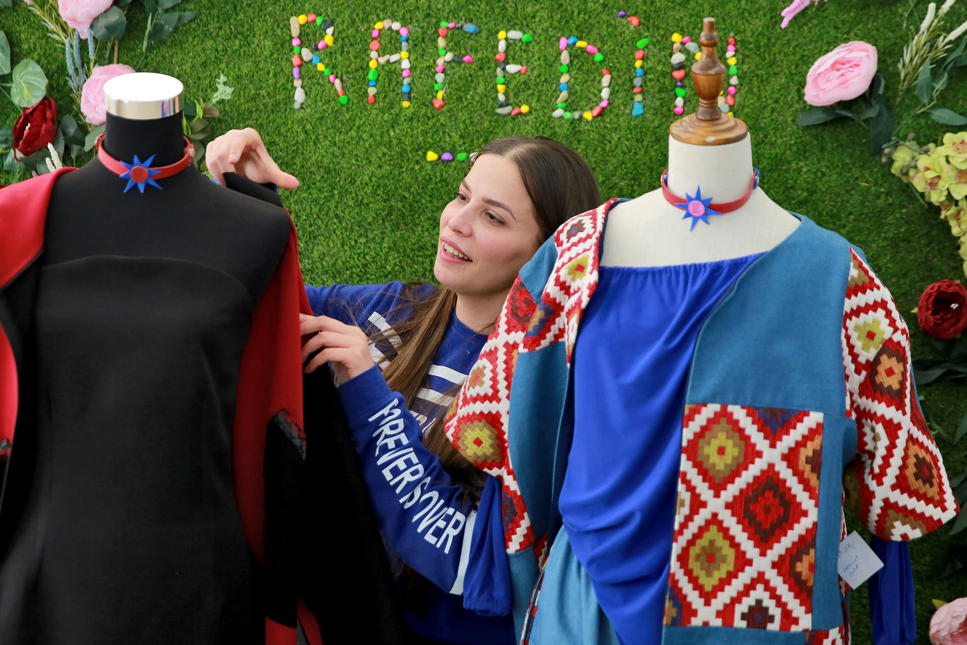 Sarah Nael inspects creations displayed on dressmaker's forms by "Rafedin"