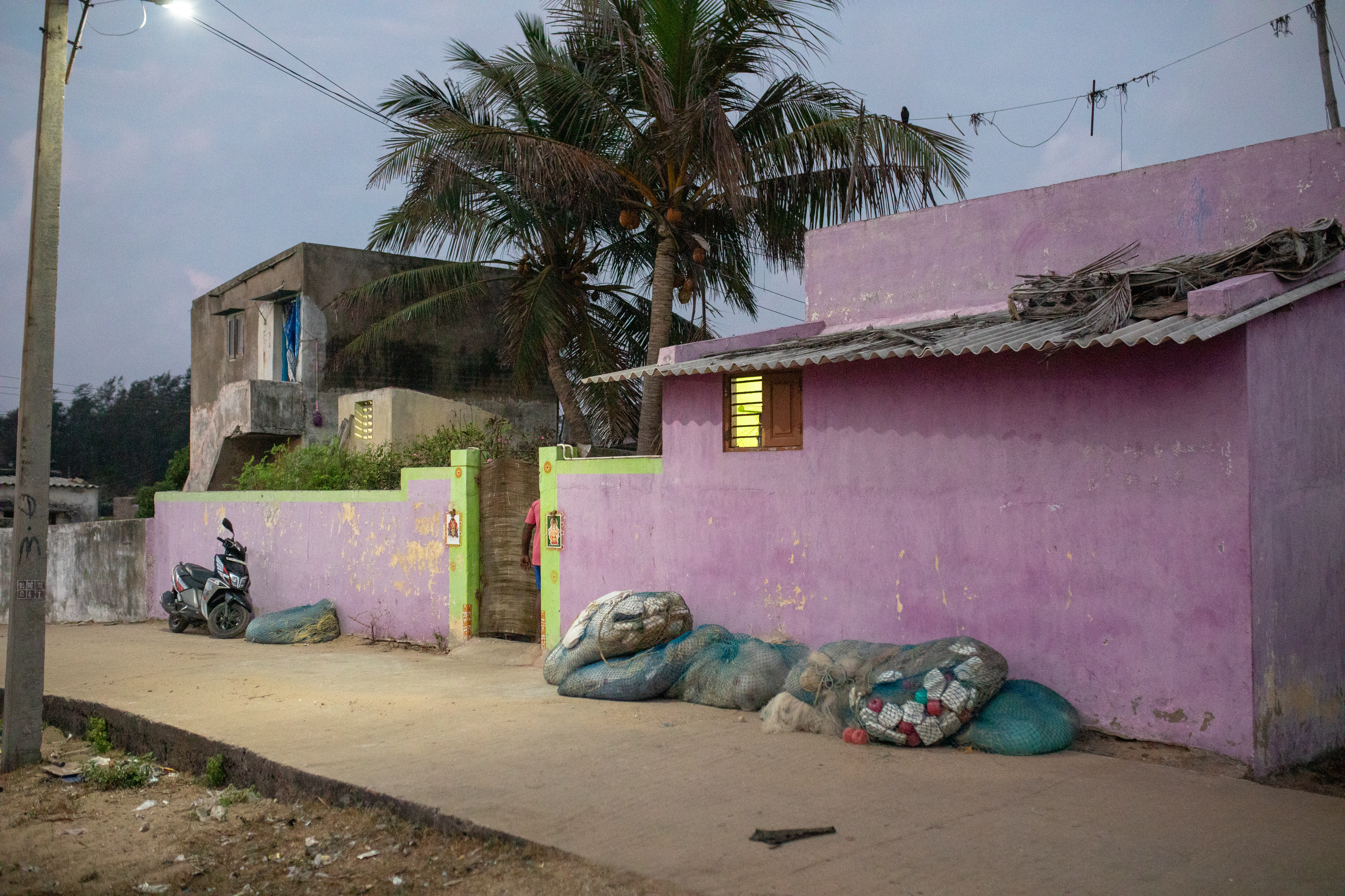 A photo of a house with bags of garbage on the wall outside.