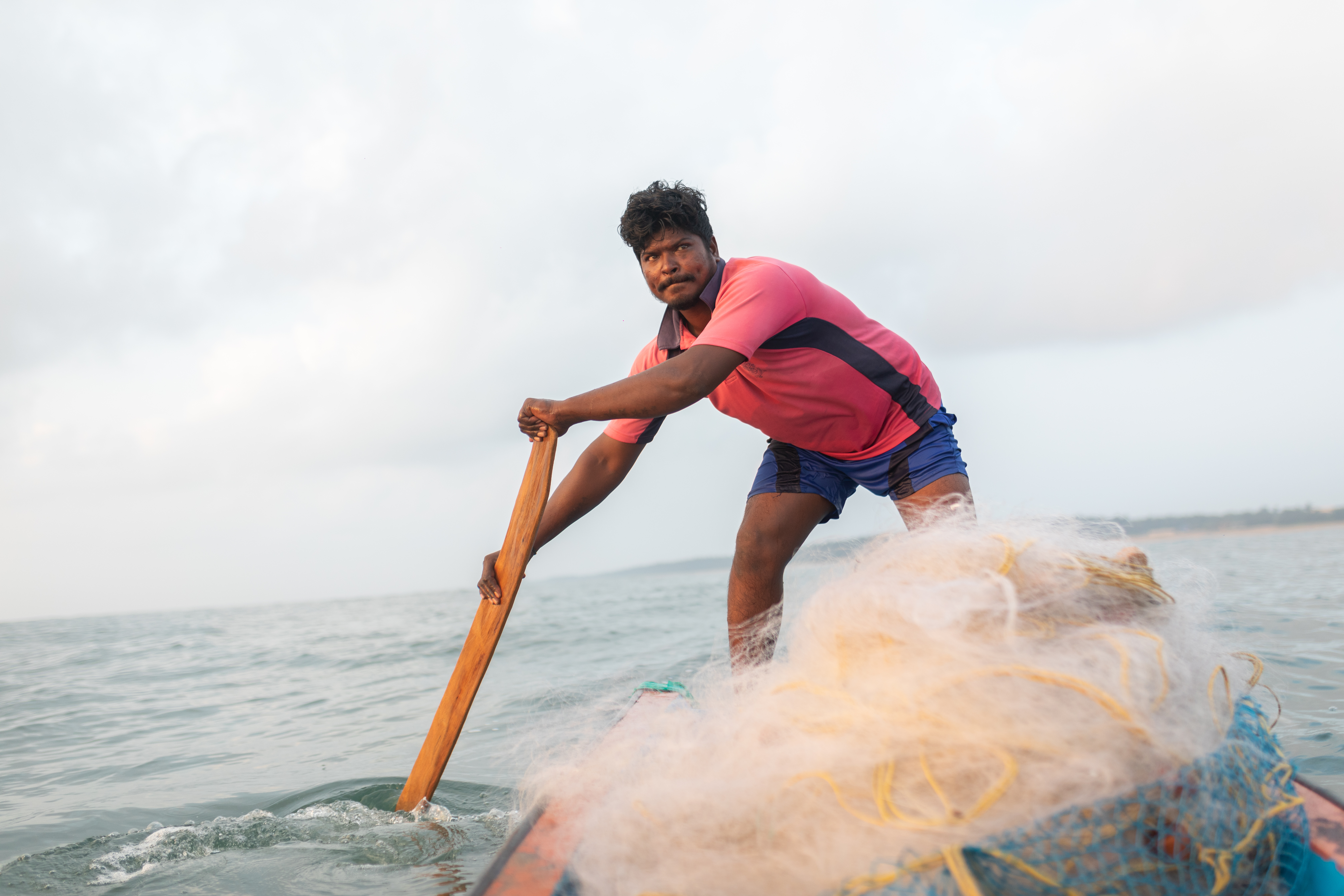 A photo of someone using a plank of wood to row a boat.