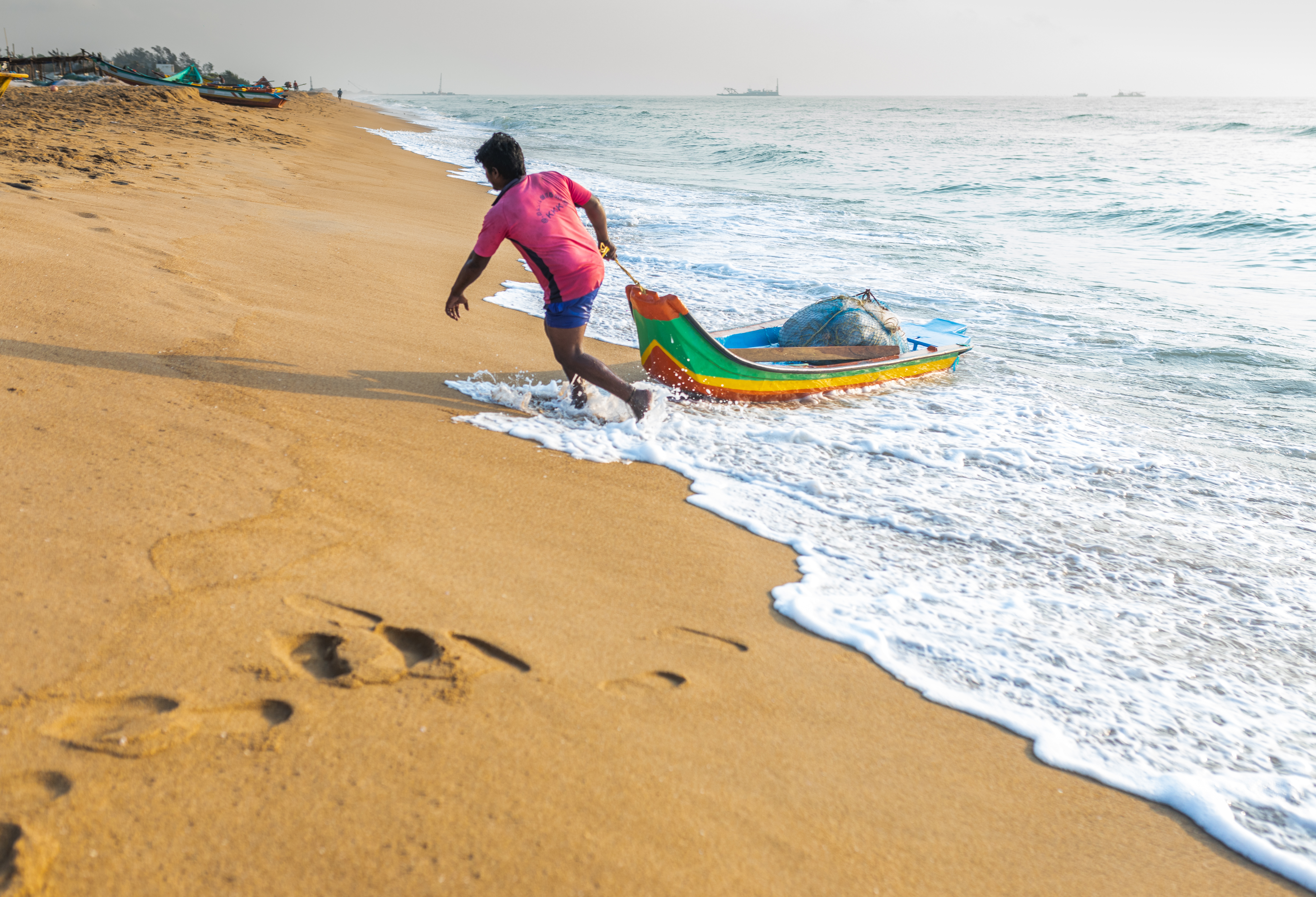A photo of someone pulling a boat out of the ocean.