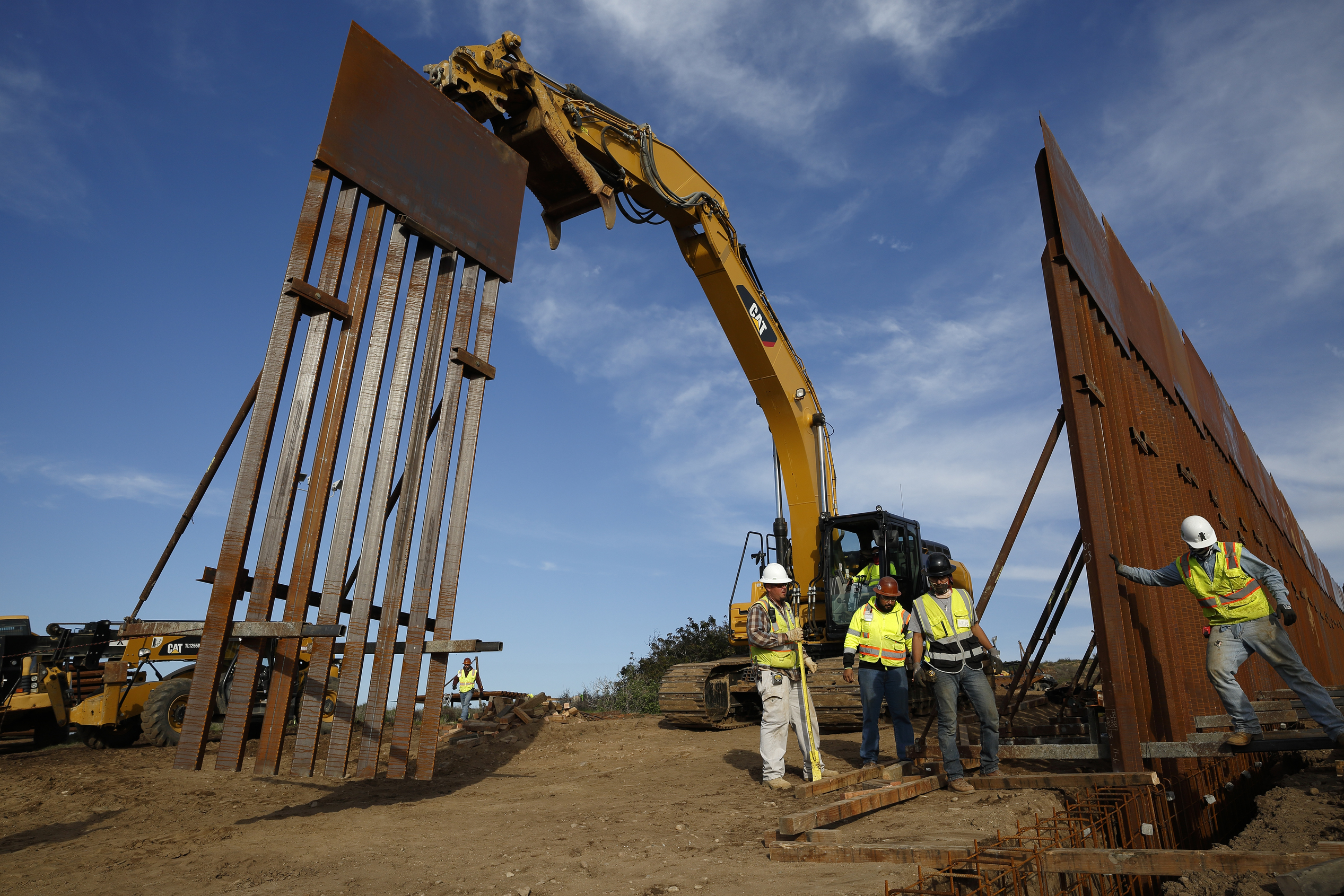 Construction workers and equipment install a border wall near Tijuana, Mexico
