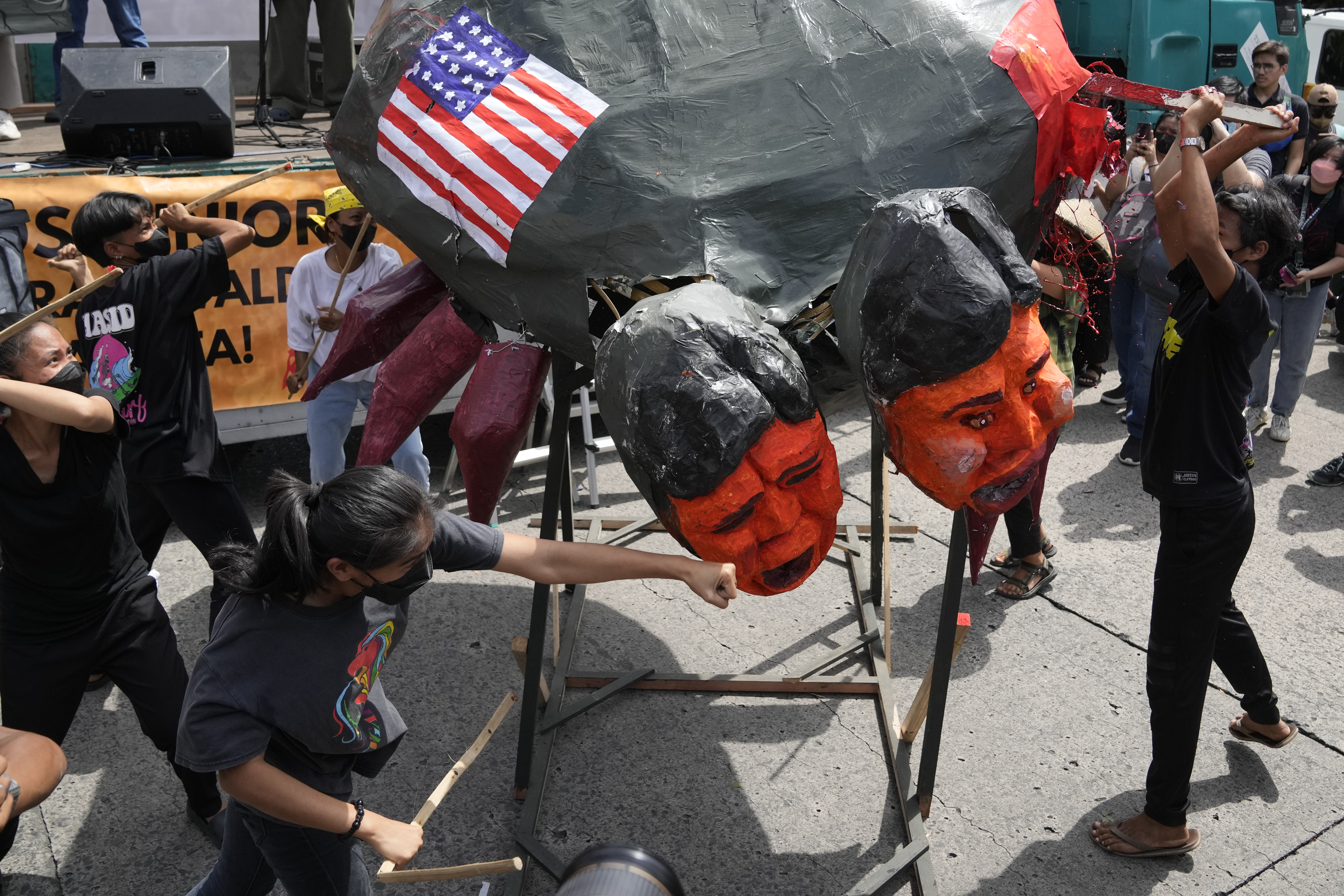 Demonstrators punch an effigy of Ferdinand Marcos Jr. It is also painted with a US flag.