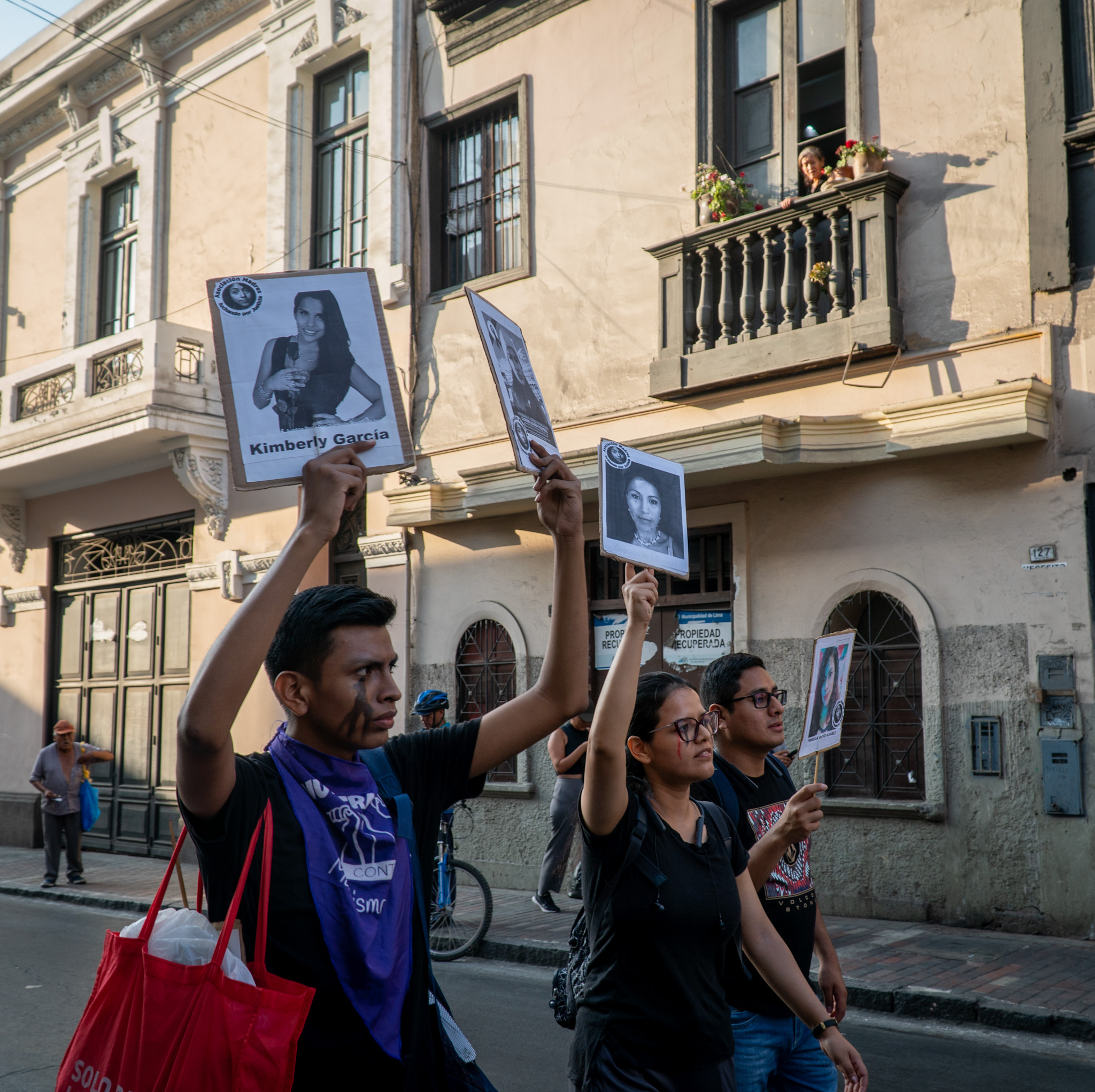 Protesters raise picket signs featuring the faces of women killed or injured in gender-based violence