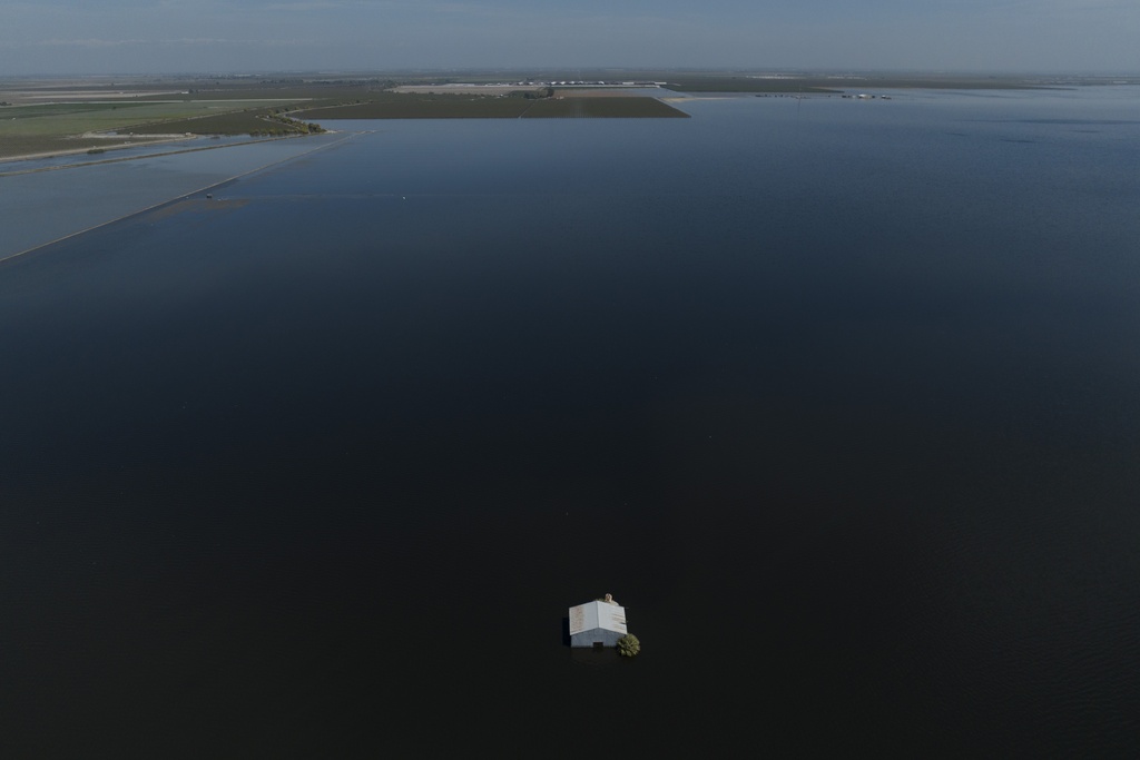A lone building pokes out of the water amid submerged farmland in California