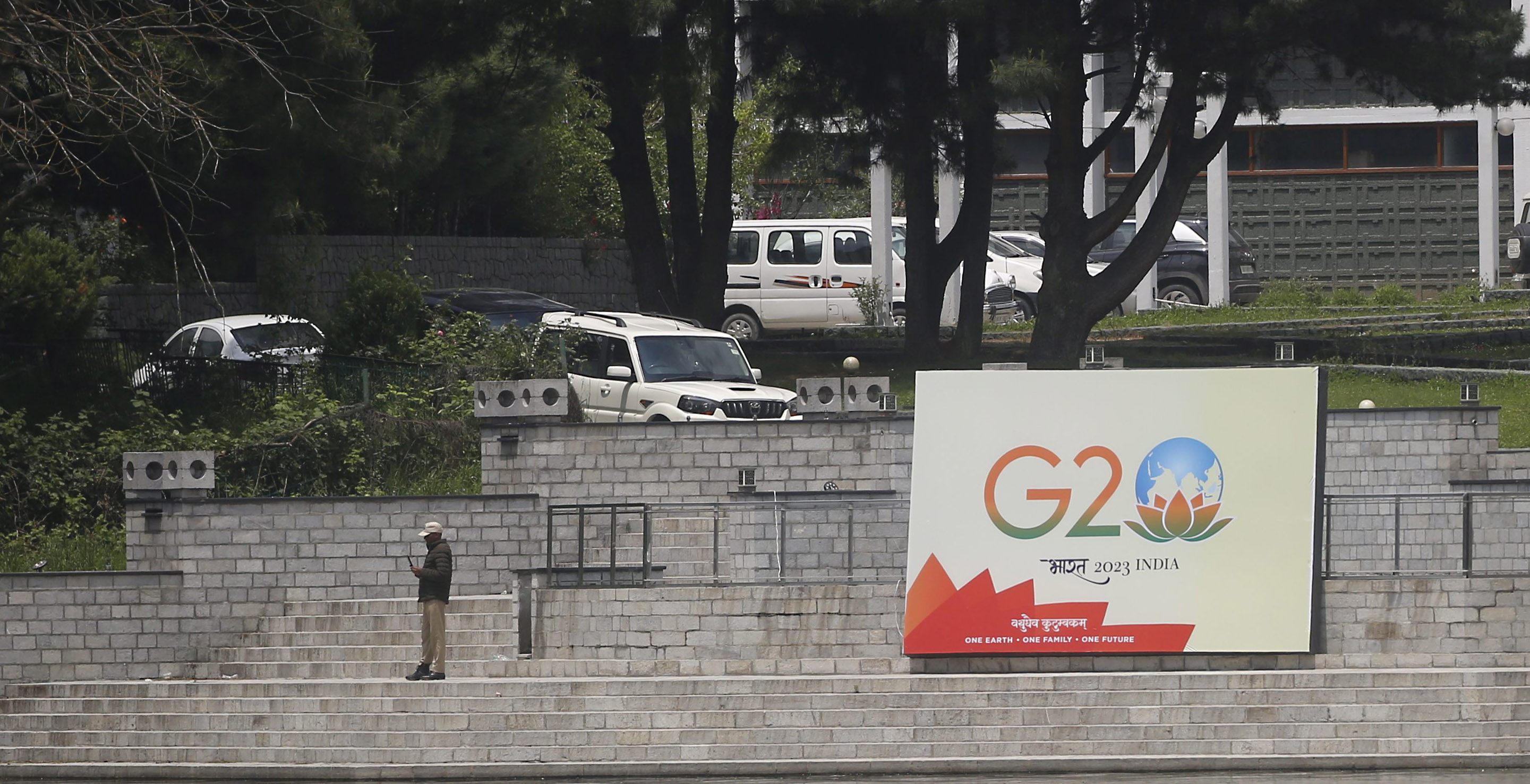 An Indian policeman stands guard next to a G20 placard on the banks of Dal Lake in Srinagar