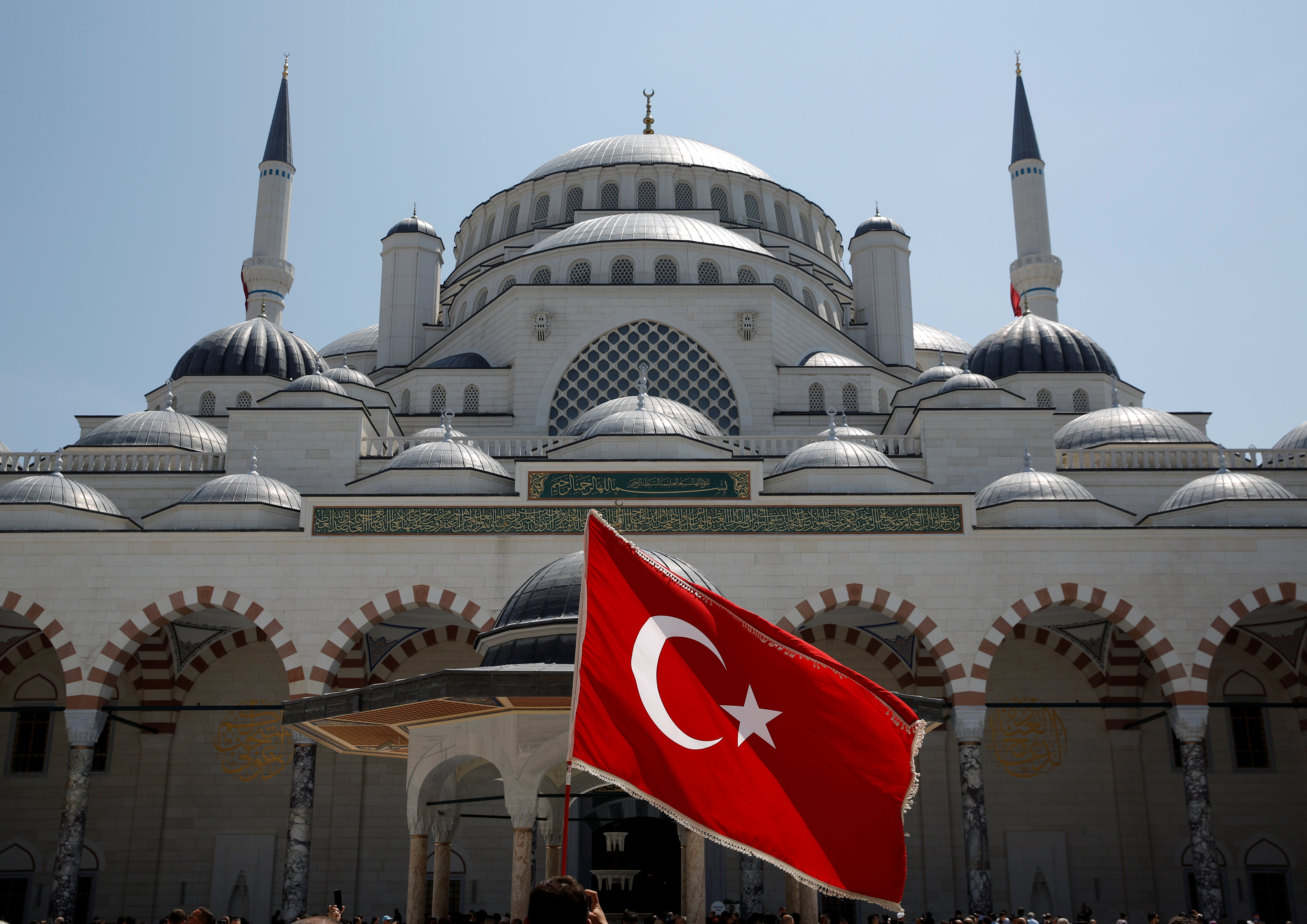 A man waves a Turkish flag at the courtyard of the Grand Camlica Mosque in Istanbul, Turkey
