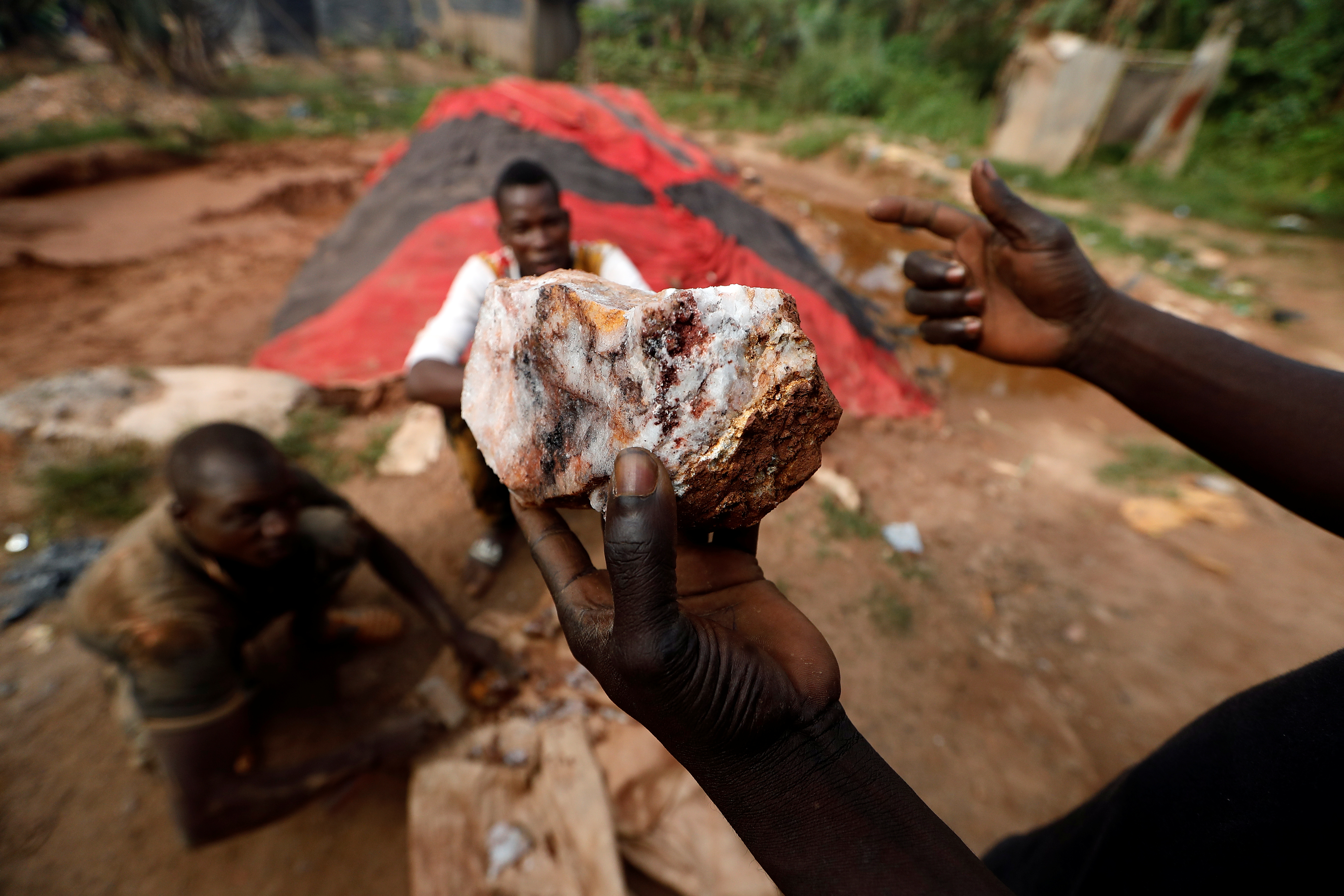 An artisanal gold miner holds up a rock recovered from inside a gold mine before it is ground down for processing at the site of Nsuaem-Top, Ghana