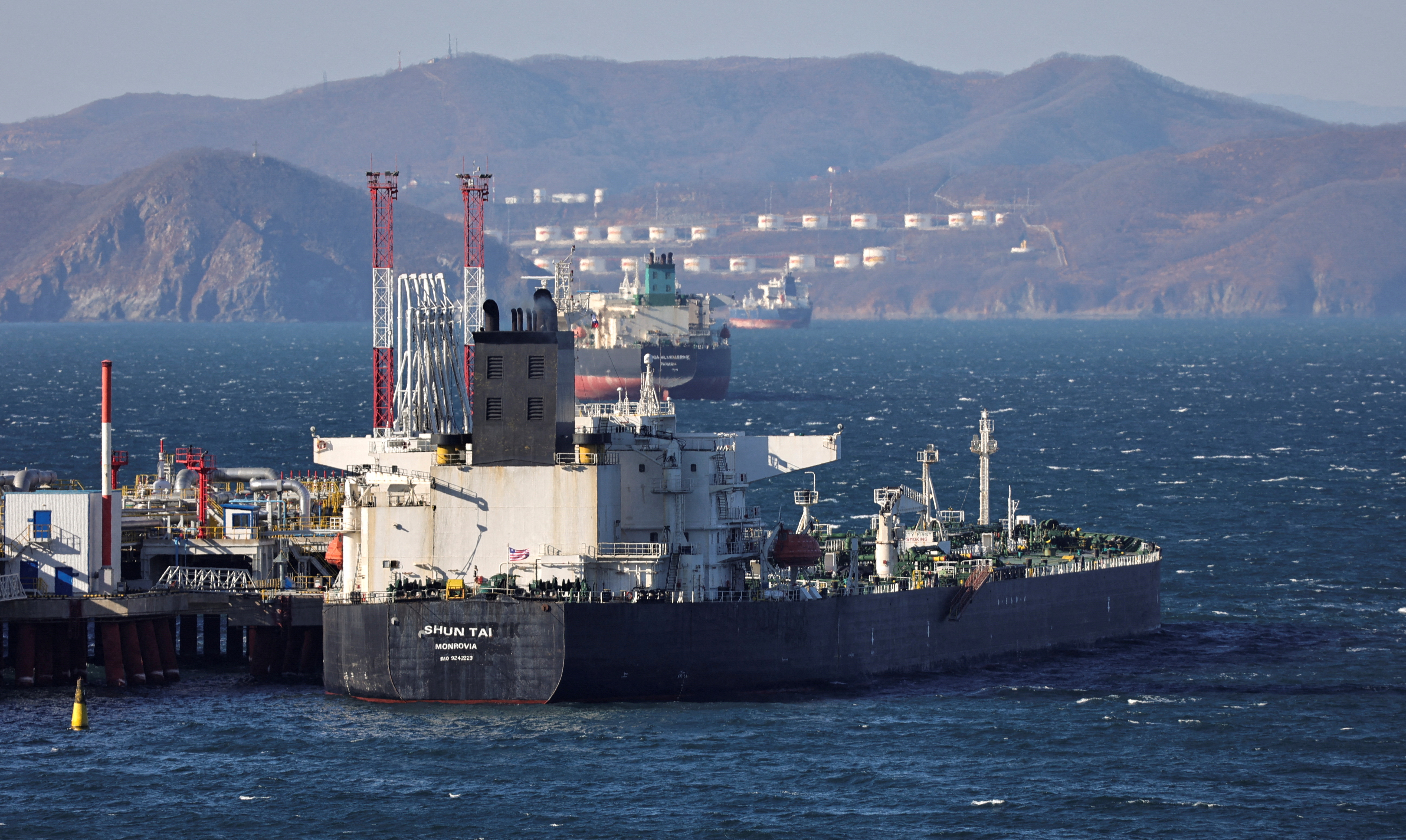 A crude oil tanker at the Kozmino terminal near Nakhodka in Russia. There are hills and gas storage tanks on the other side of the bay