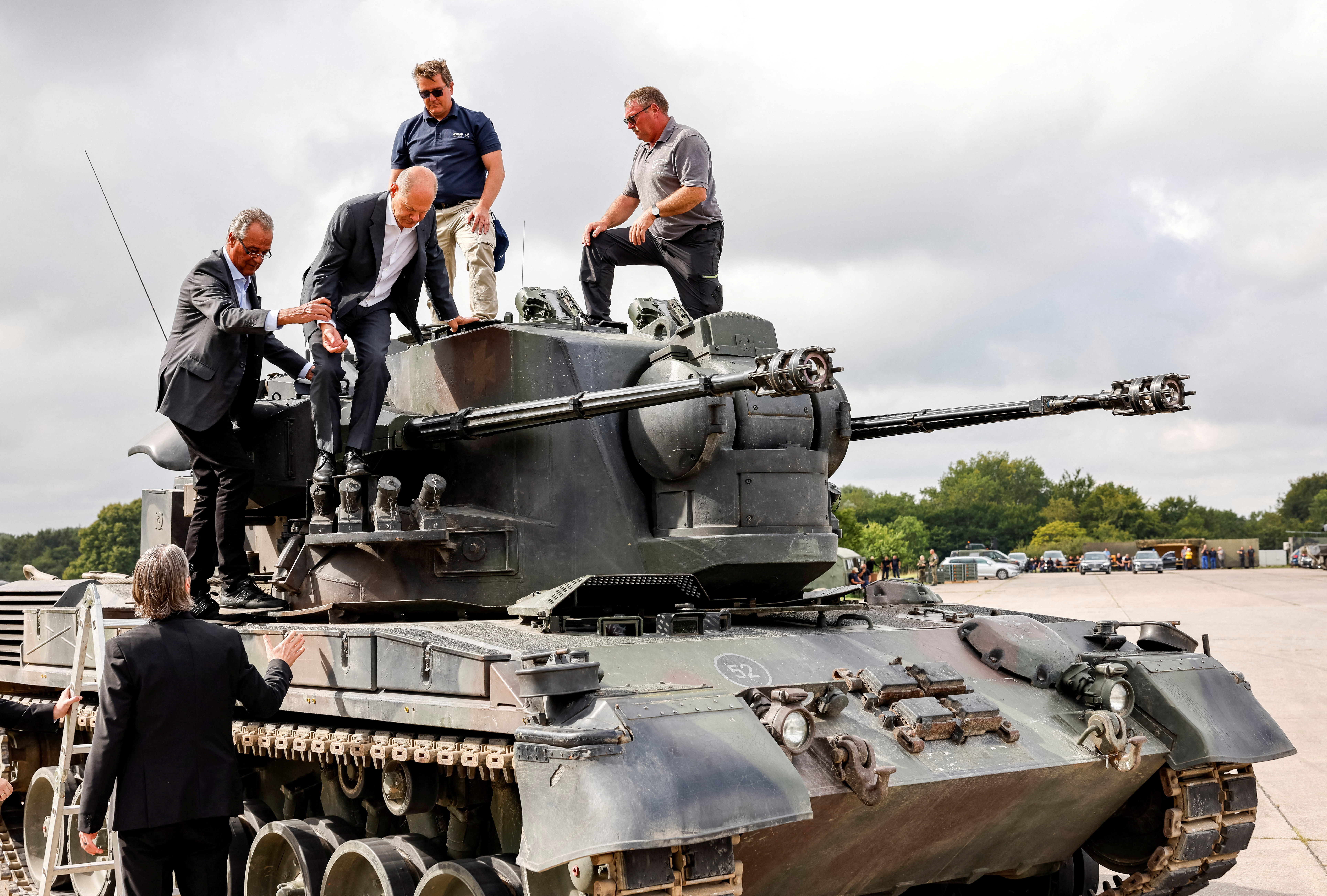 German Chancellor Olaf Scholz gets off a German self-propelled anti-aircraft gun Flakpanzer Gepard with head of training at arms manufacturer Krauss-Maffei Juergen Schoch and CEO of Nexter Defense Systems Frank Haun, during a visit of the training program for Ukrainian soldiers on the Gepard anti-aircraft tank in Putlos near Oldenburg, Germany August 25, 2022.