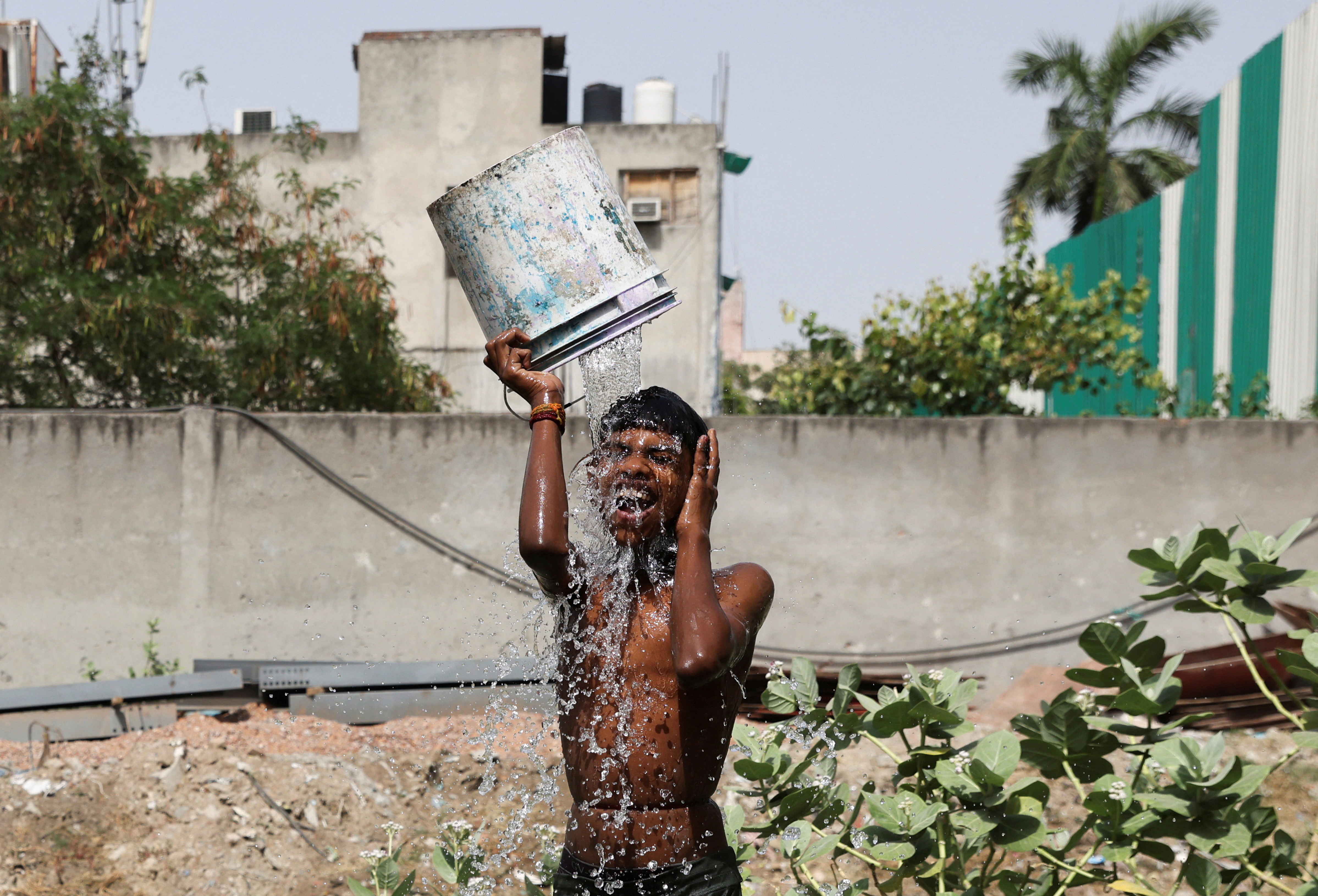 A boy bathes outside his residence on a hot summer day in New Delhi, India, May 22, 2023.