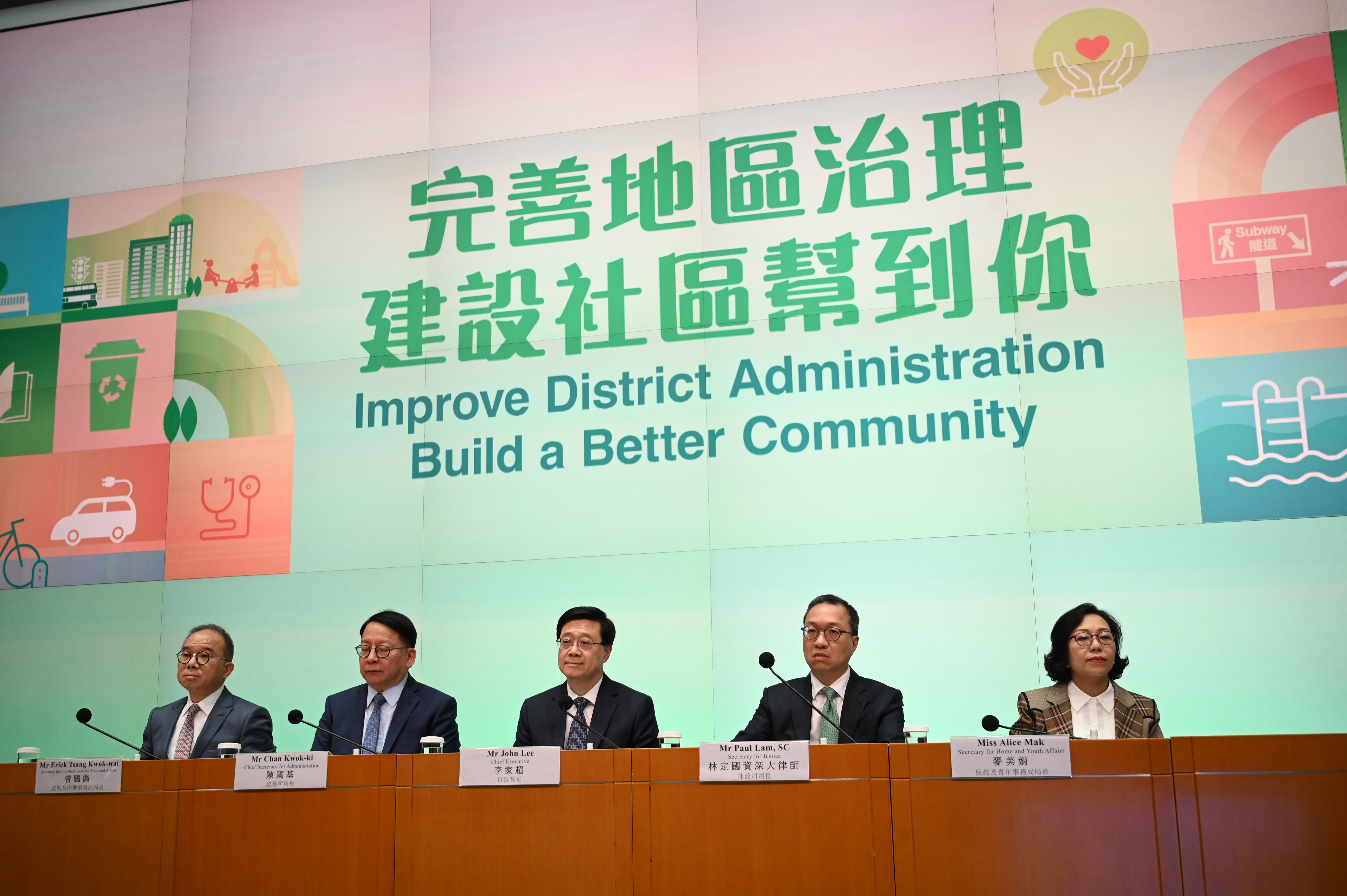 John Lee and four officials at a desk in front of a sign in green reading: Improve District Administration Build a Better Community
