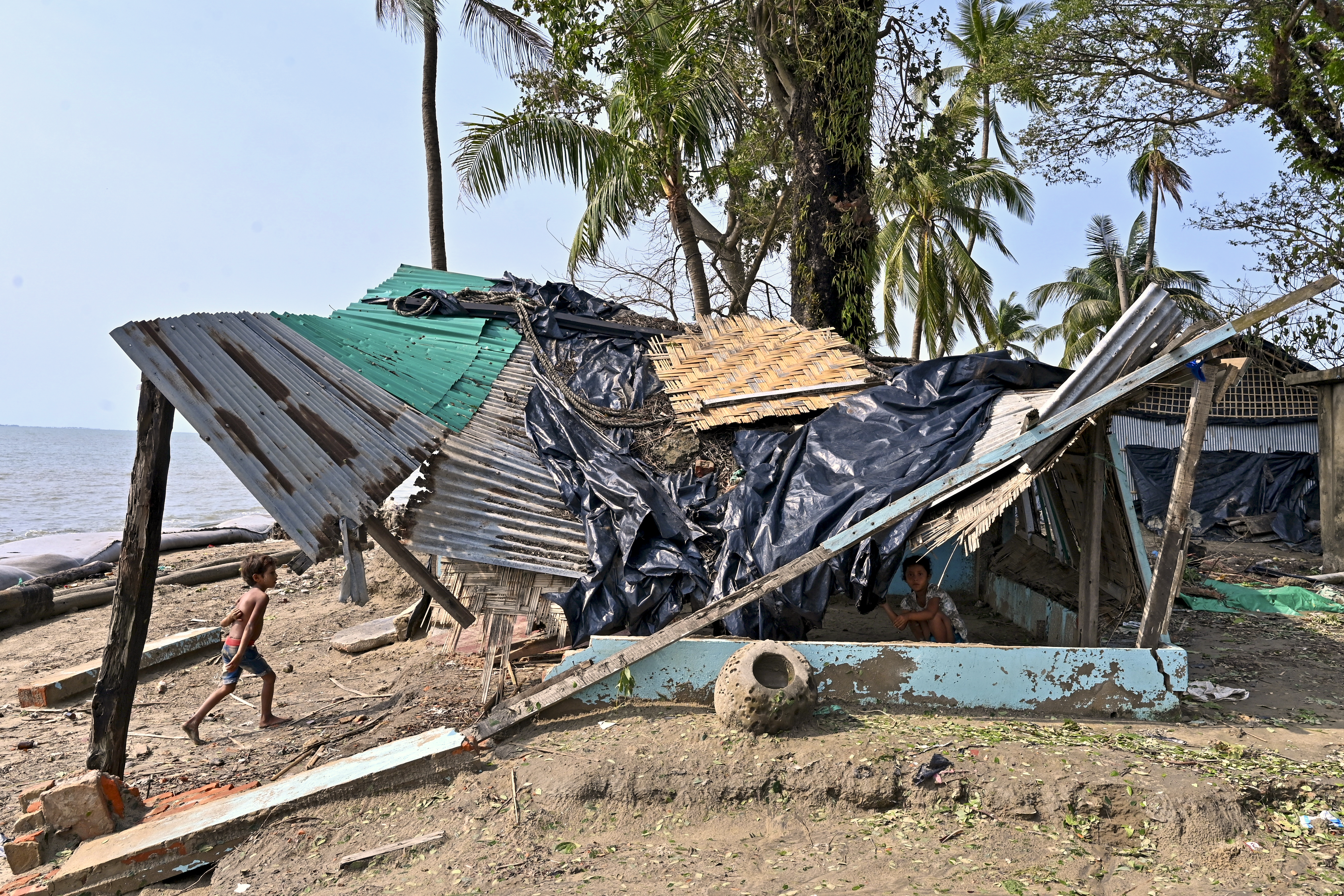 A boy walks beside a house which was partially destroyed by cyclone Mocha, in Shahpori island on the outskirts of Teknaf