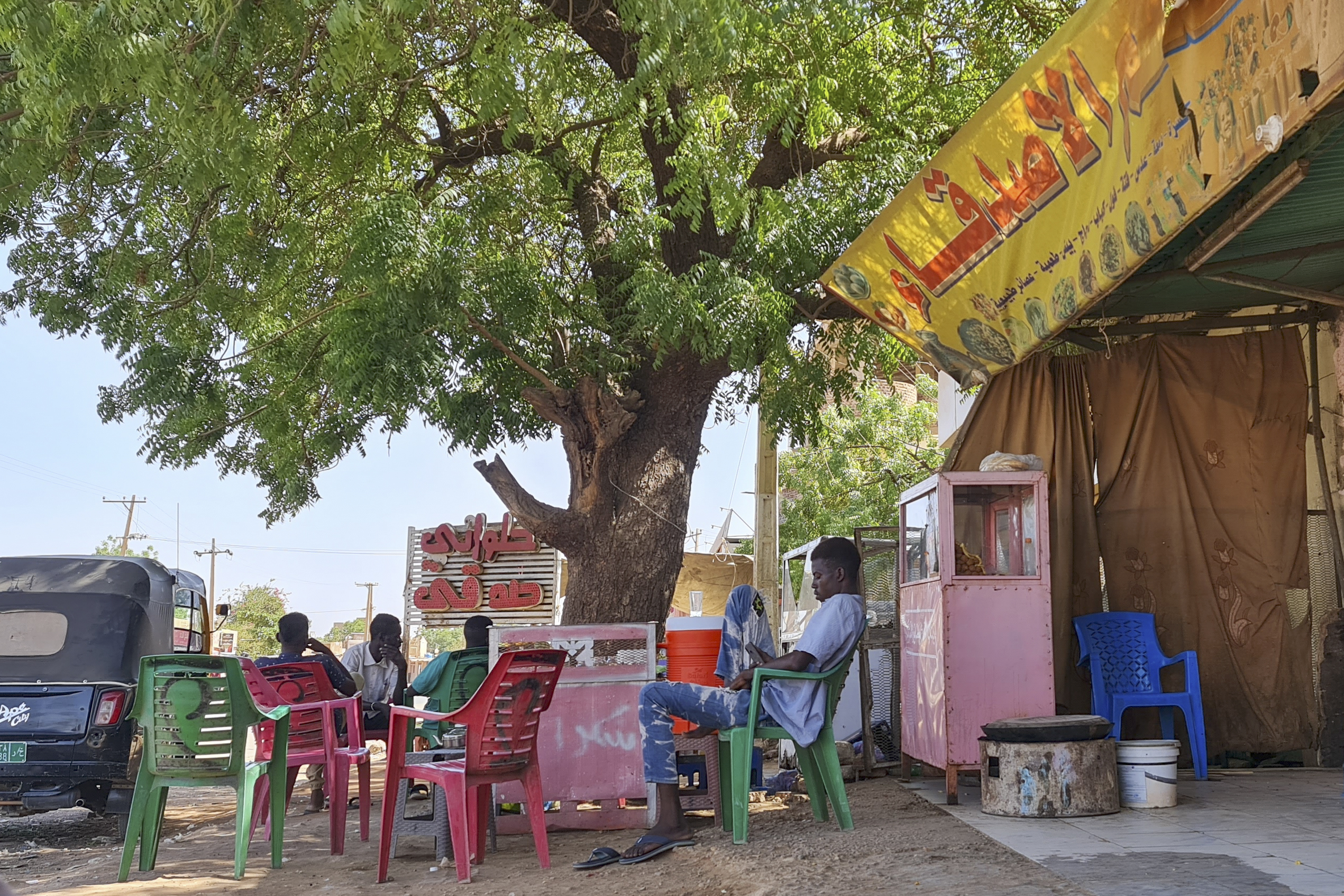 People rest under a tree in a roadside coffee shop in southern Khartoum