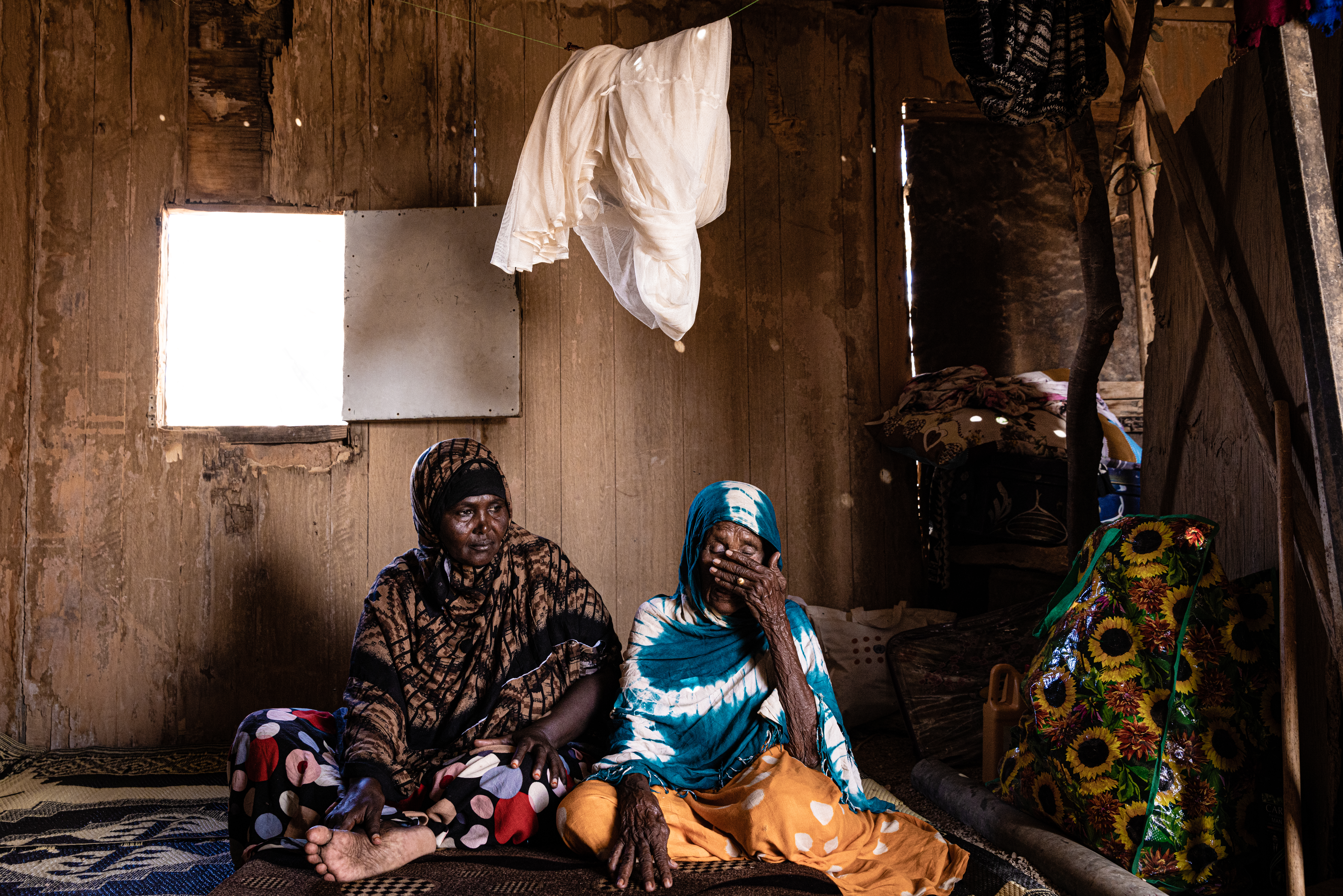 Asha Awad Jama with her elderly mother in a room they share with other displaced families.
