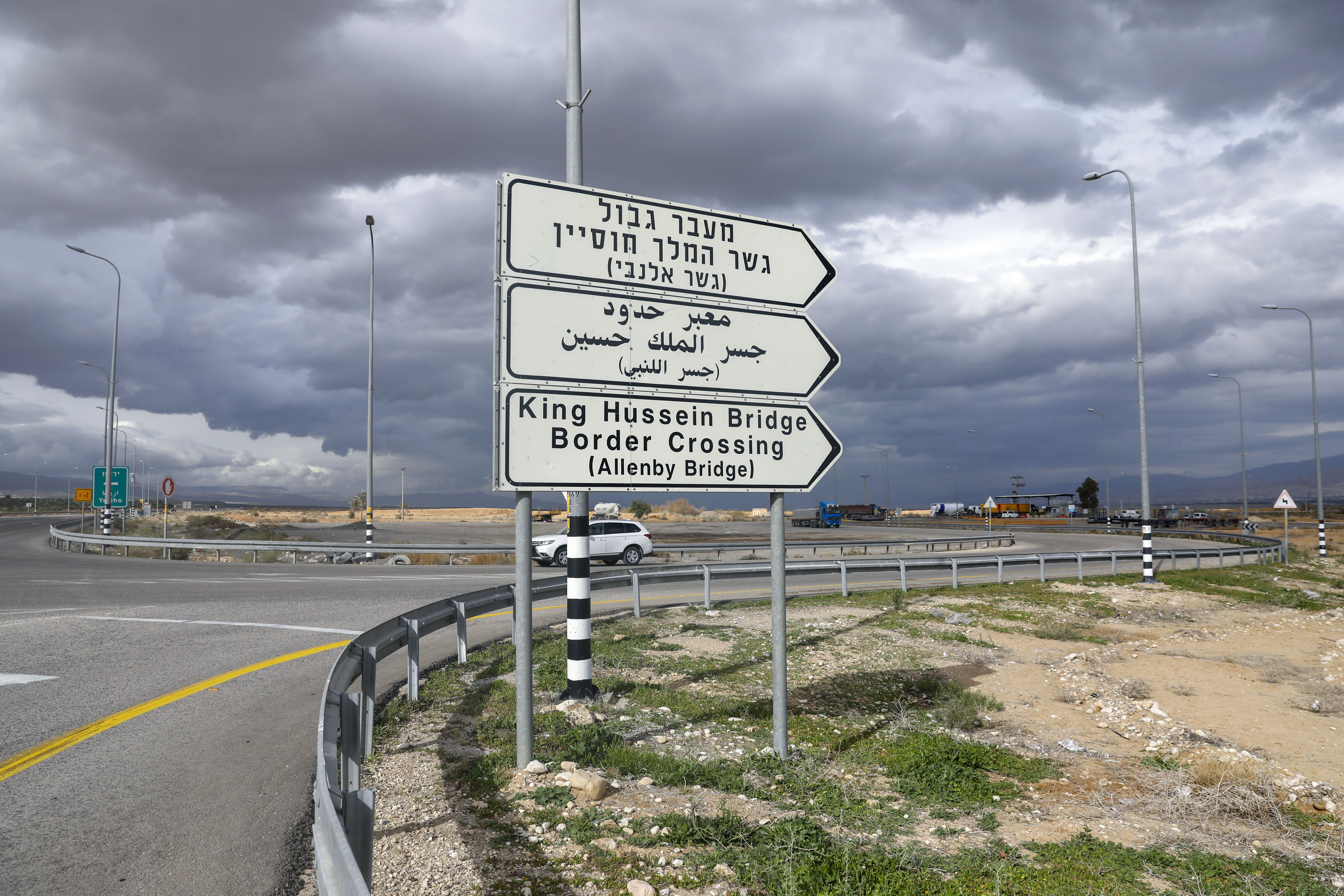 A car drives past a sign for the King Hussein Bridge