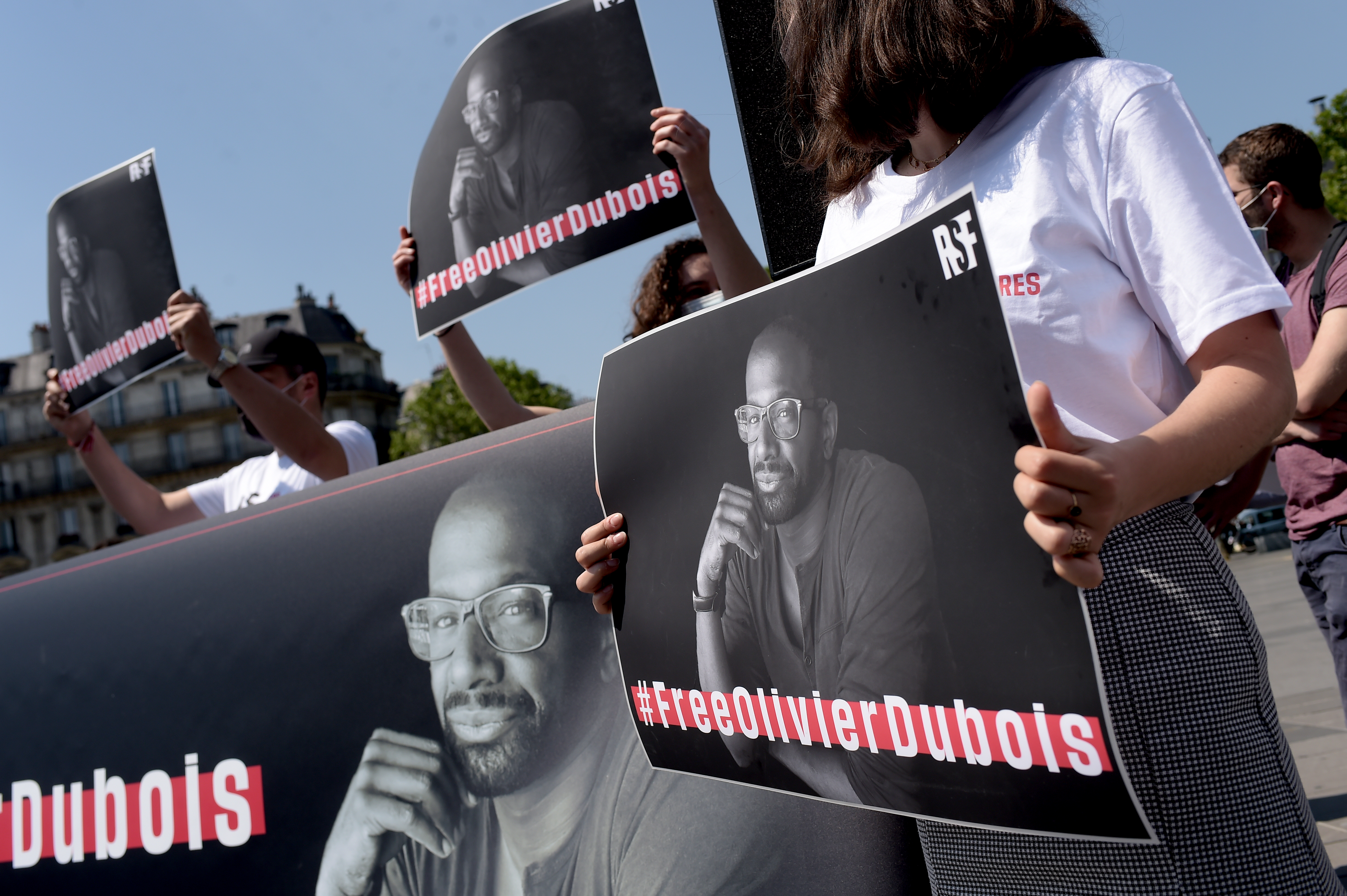 People hold placards with a portrait of French journalist Olivier Dubois in Paris on June 8, 2021.