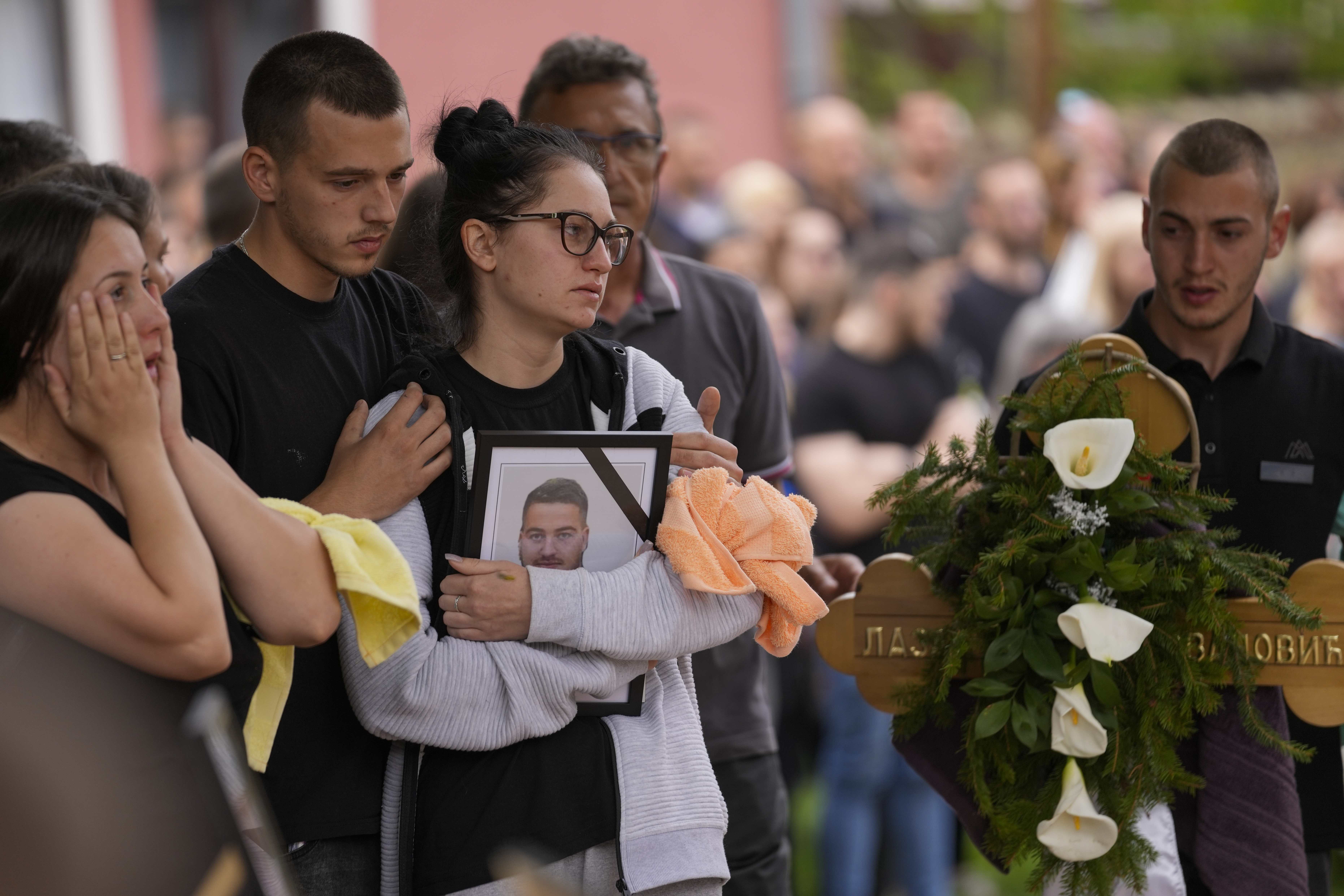 Relatives of a victim carry a photo during a funeral for five people killed during the second mass shooting in two days, in the village of Malo Orasje, some 50 kilometers (30 miles) south of Belgrade, Serbia, Saturday, May 6, 2023. In Thursday's attack, a 20-year-old gunman apparently firing at random, killed eight people and wounded 14 in two Serbian villages. (AP Photo/Darko Vojinovic)